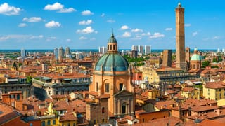 Bologna skyline with its leaning medieval Two Towers, a green-domed church and terracotta rooftops