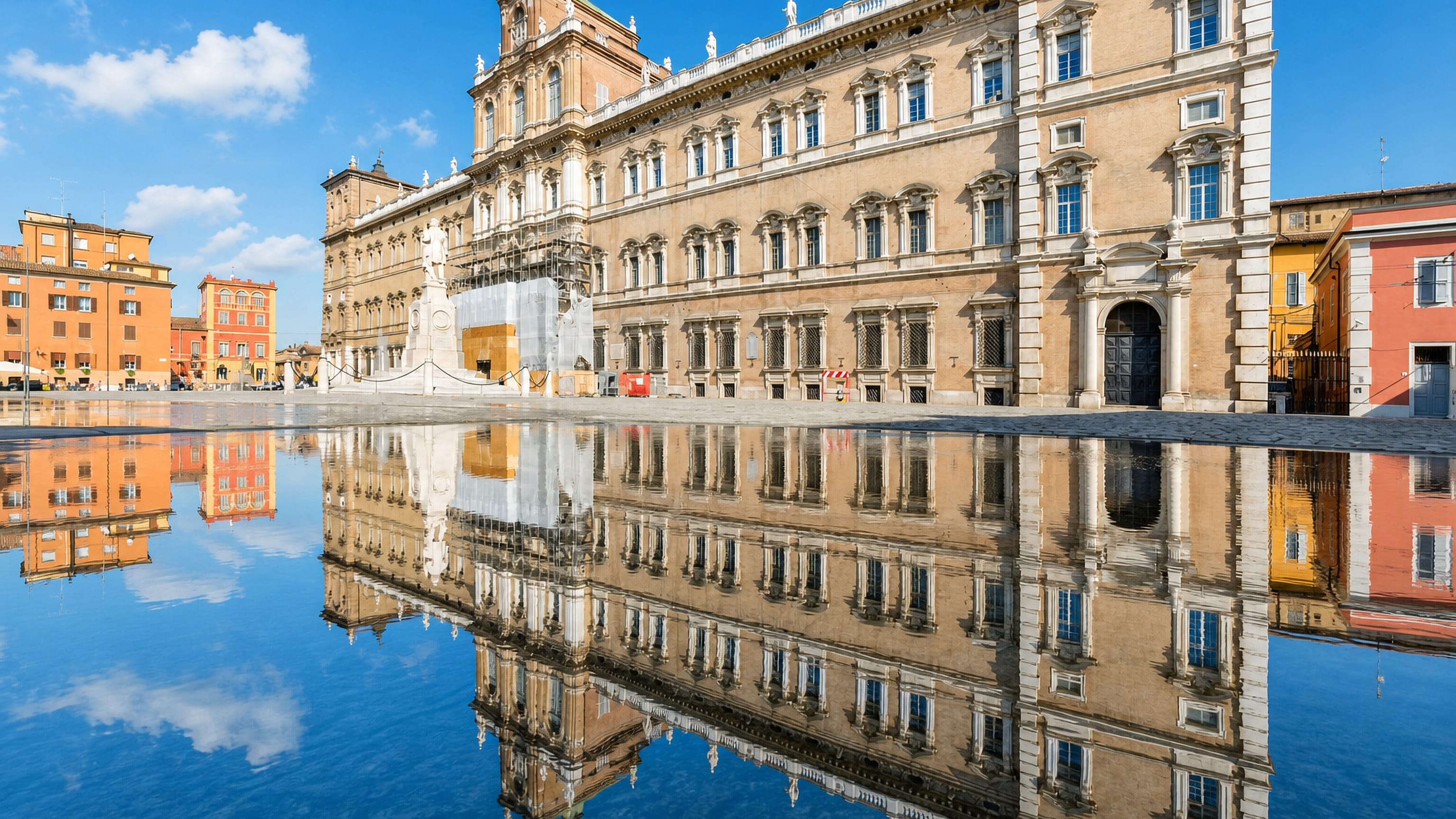 Modena's baroque Palazzo Ducale on Piazza Roma, its long sandstone facade mirrored in water below.