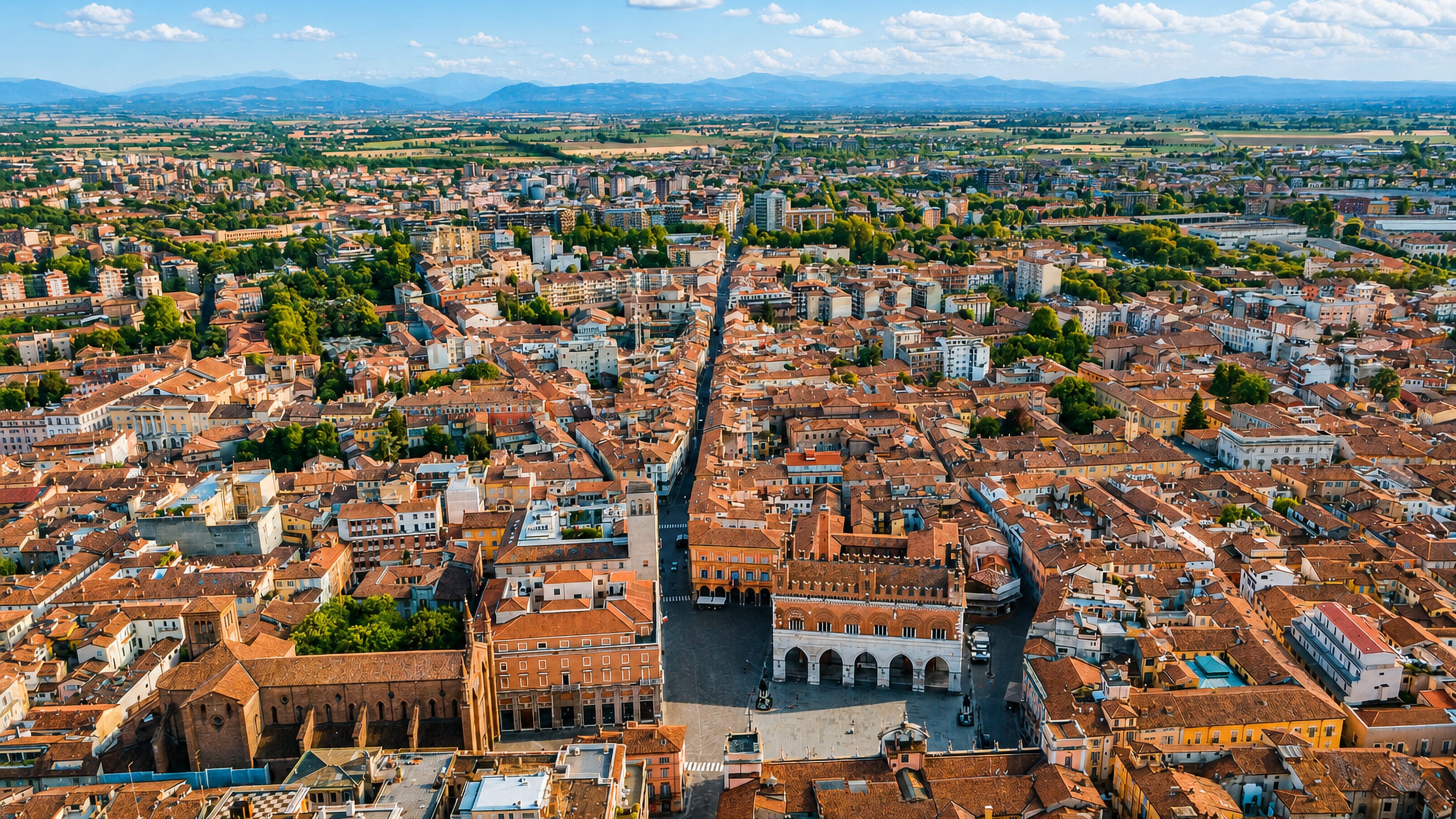 Aerial view of Piacenza's Piazza Cavalli and the arcaded Palazzo Gotico amid the city's terracotta rooftops.