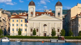 Trieste waterfront with the twin-towered Greek Orthodox Church of San Nicolò and boats moored on the Adriatic.