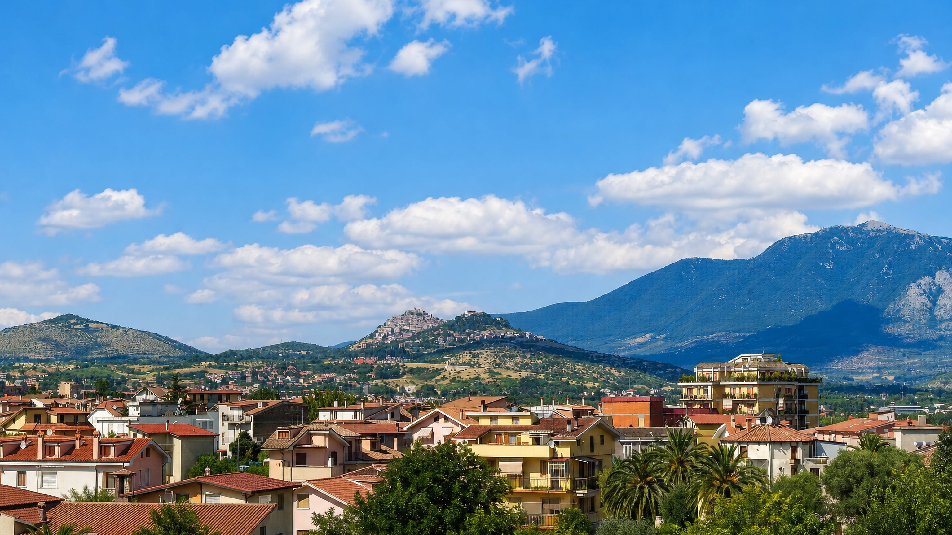 Tiled rooftops of Guidonia Montecelio, Italy, below the hilltop old town and the surrounding mountains.