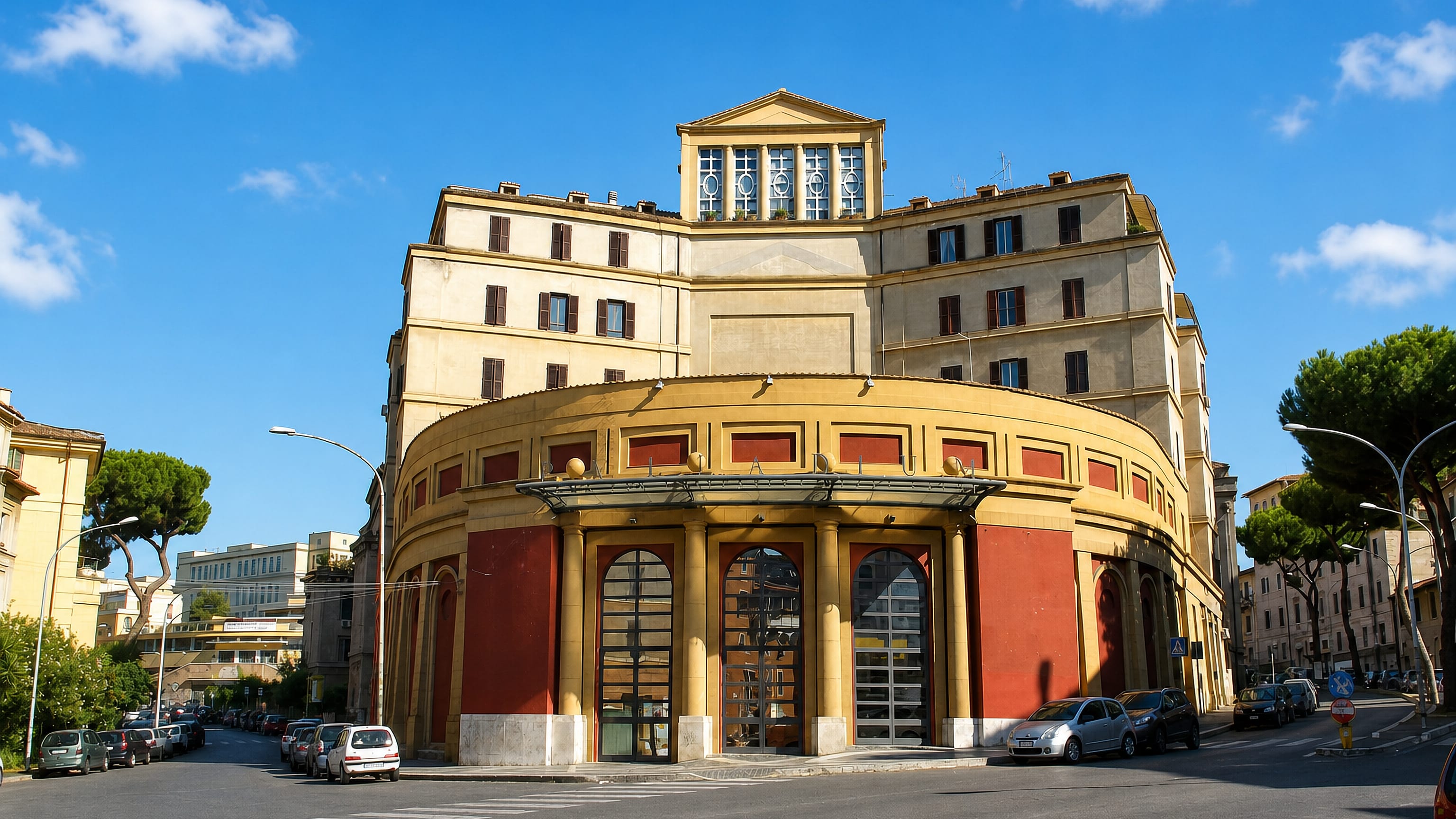 Curved ochre and red rationalist facade on a street corner in Rome's Garbatella district.