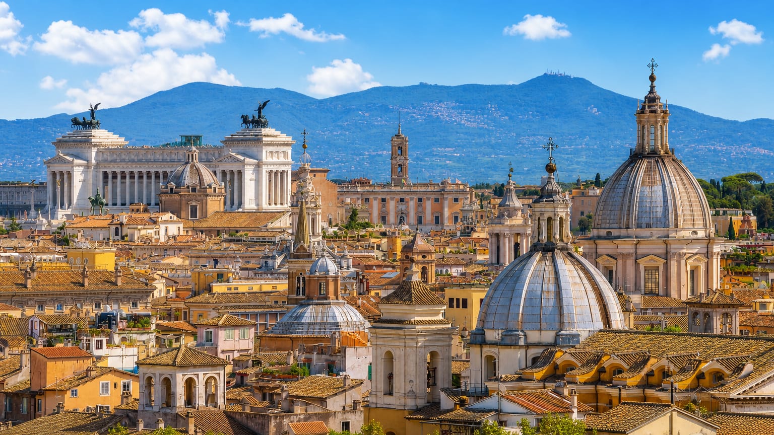Rome skyline with the Altare della Patria monument, church domes and rooftops backed by hills under a blue sky