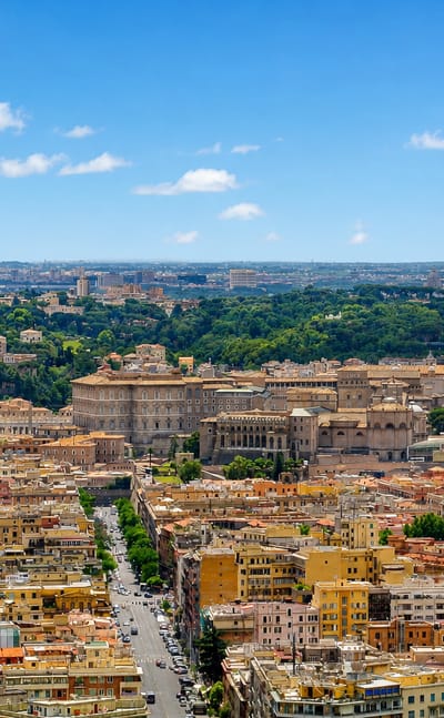 Rome's Prati district rooftops with the dome of St Peter's Basilica dominating the skyline under a blue sky