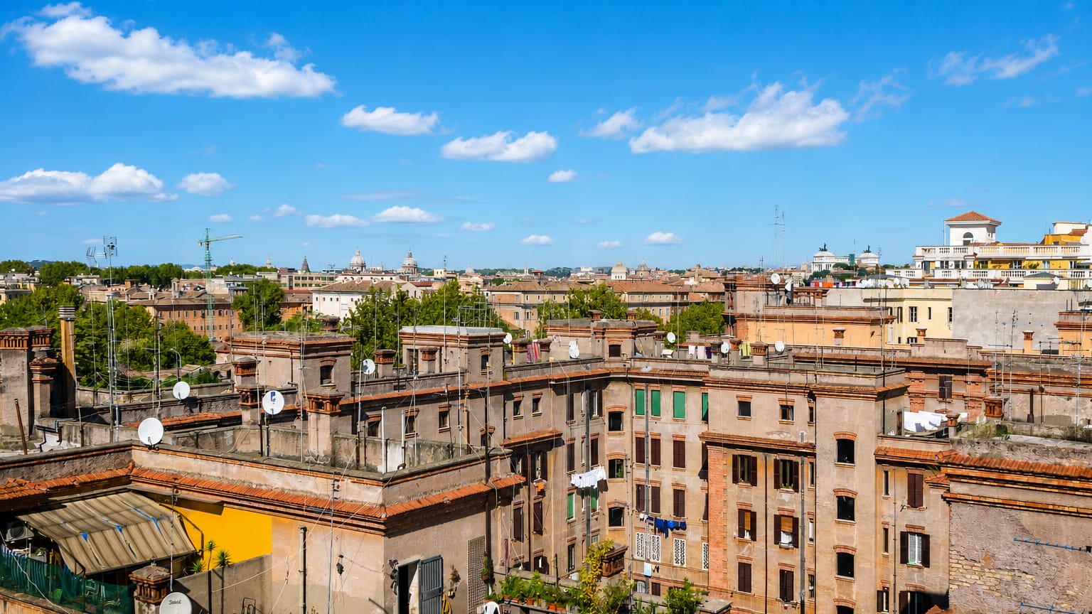 Rooftop view over Rome's Testaccio district showing terracotta-tiled buildings, satellite dishes and distant church domes.