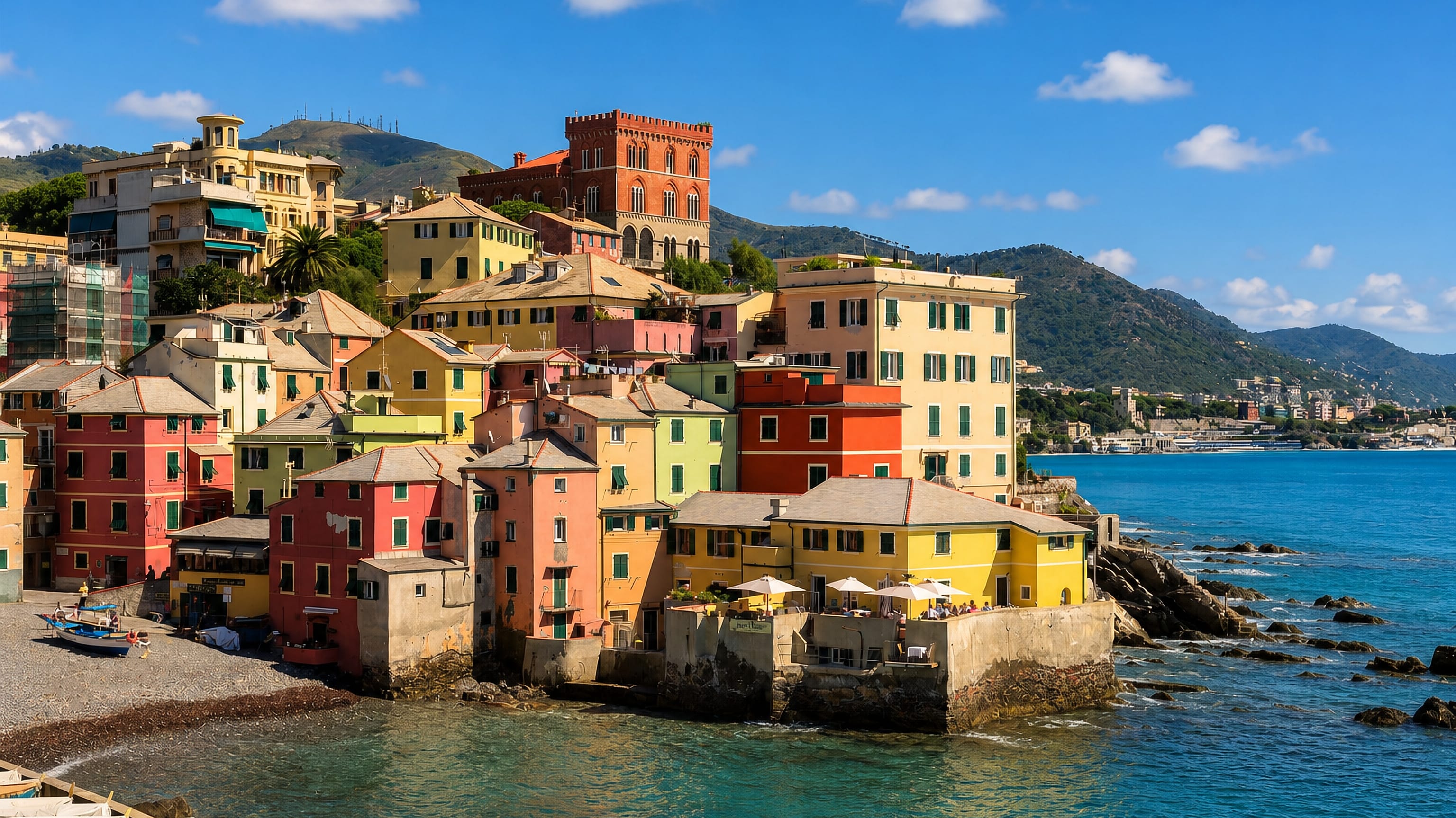 Boccadasse in Genoa, with pastel fishermen's houses and boats ringing the pebble cove below a hilltop castle.