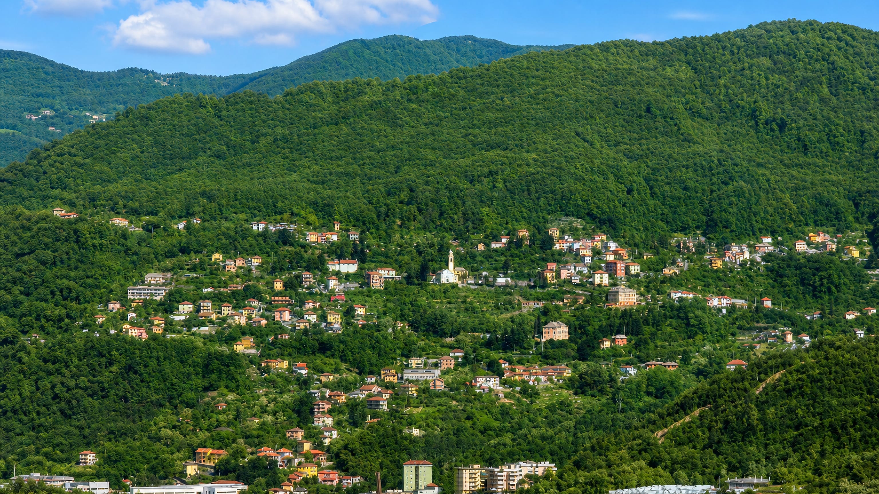 Hillside houses and a white church tower among wooded slopes at Fontanegli above the Bisagno valley, Genoa.