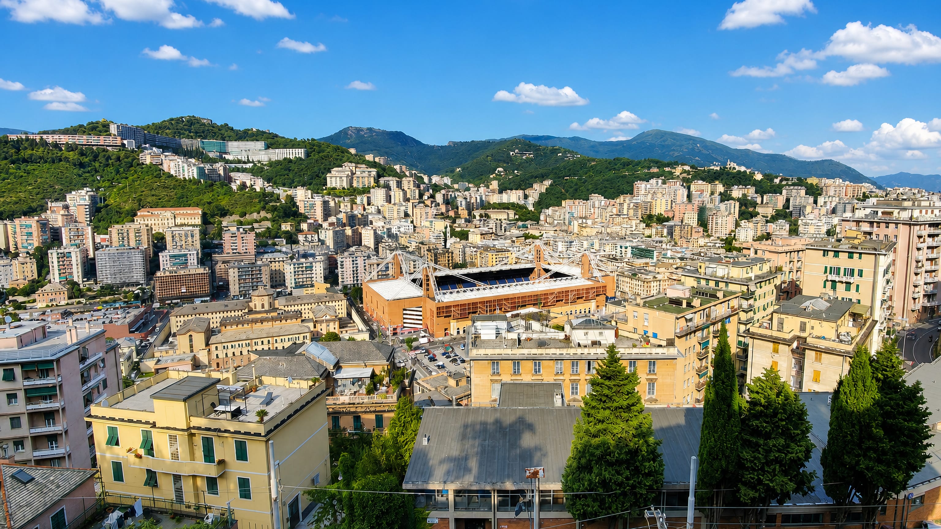 The Luigi Ferraris stadium ringed by dense hillside housing in Marassi, Genoa, with the Apennine hills behind
