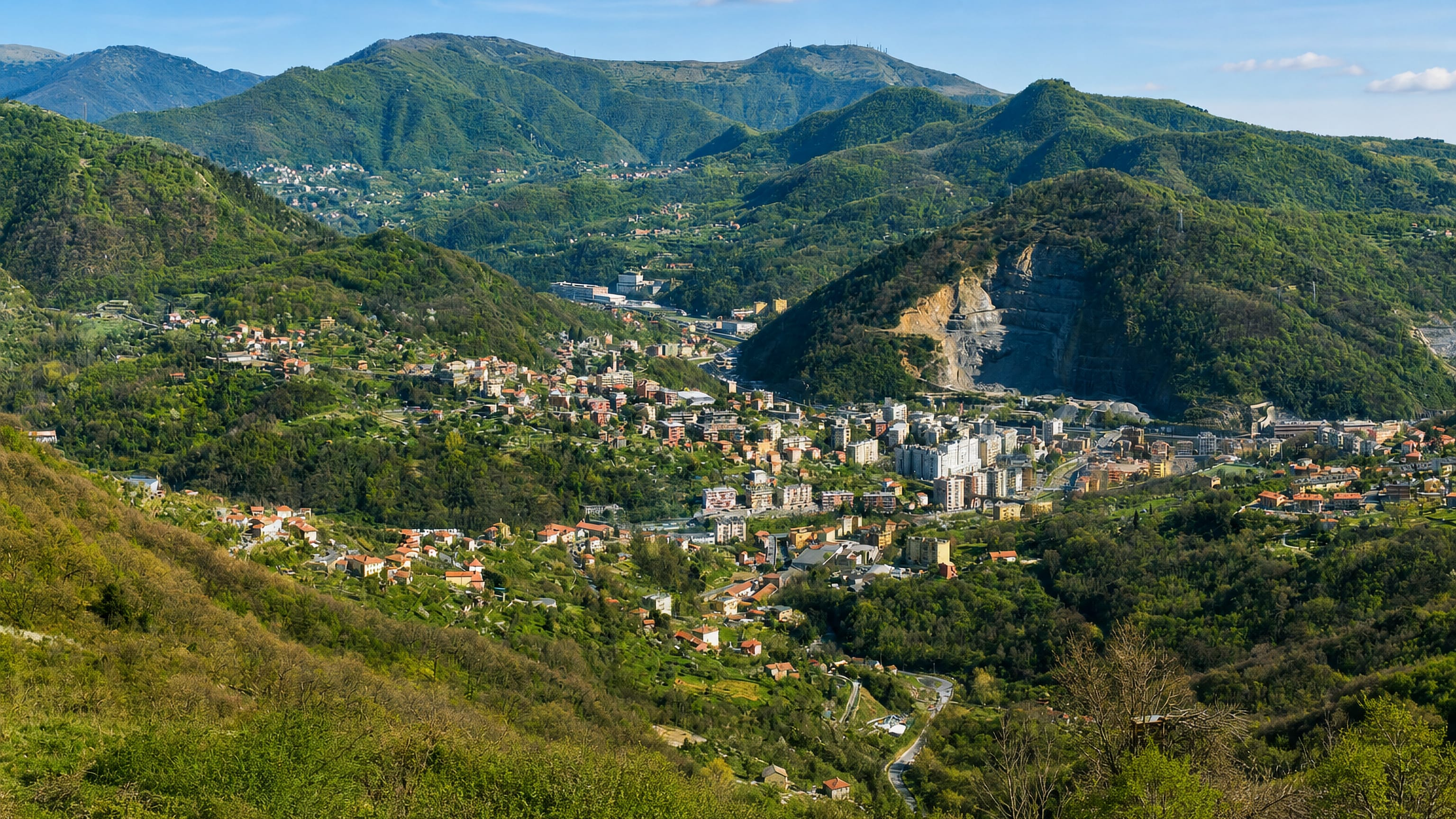 Molassana spread along the Bisagno valley floor in Genoa, ringed by green hills and a hillside quarry.