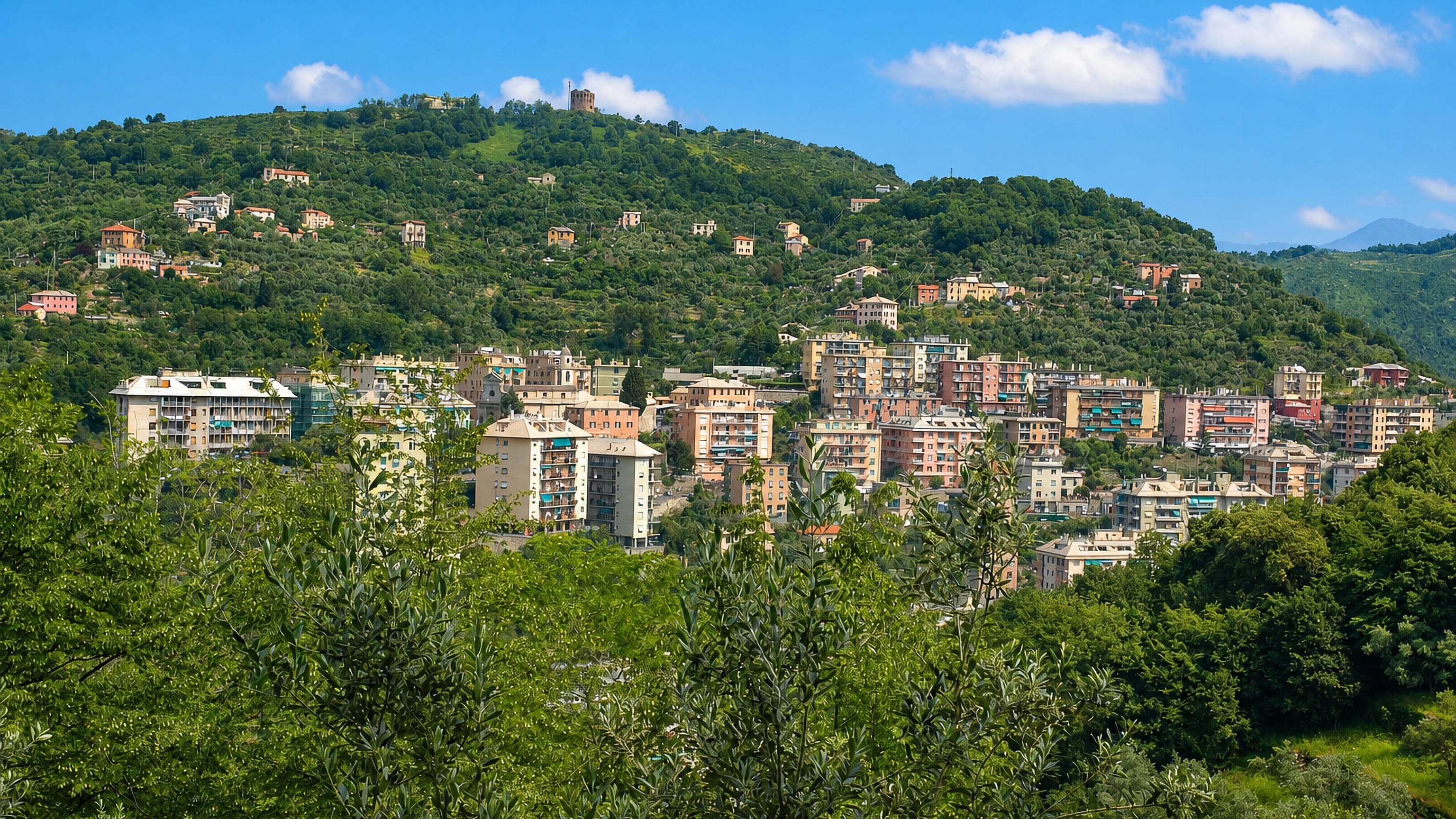 Pastel apartment blocks climbing the green hillside of Quezzi above the Bisagno valley in Genoa.