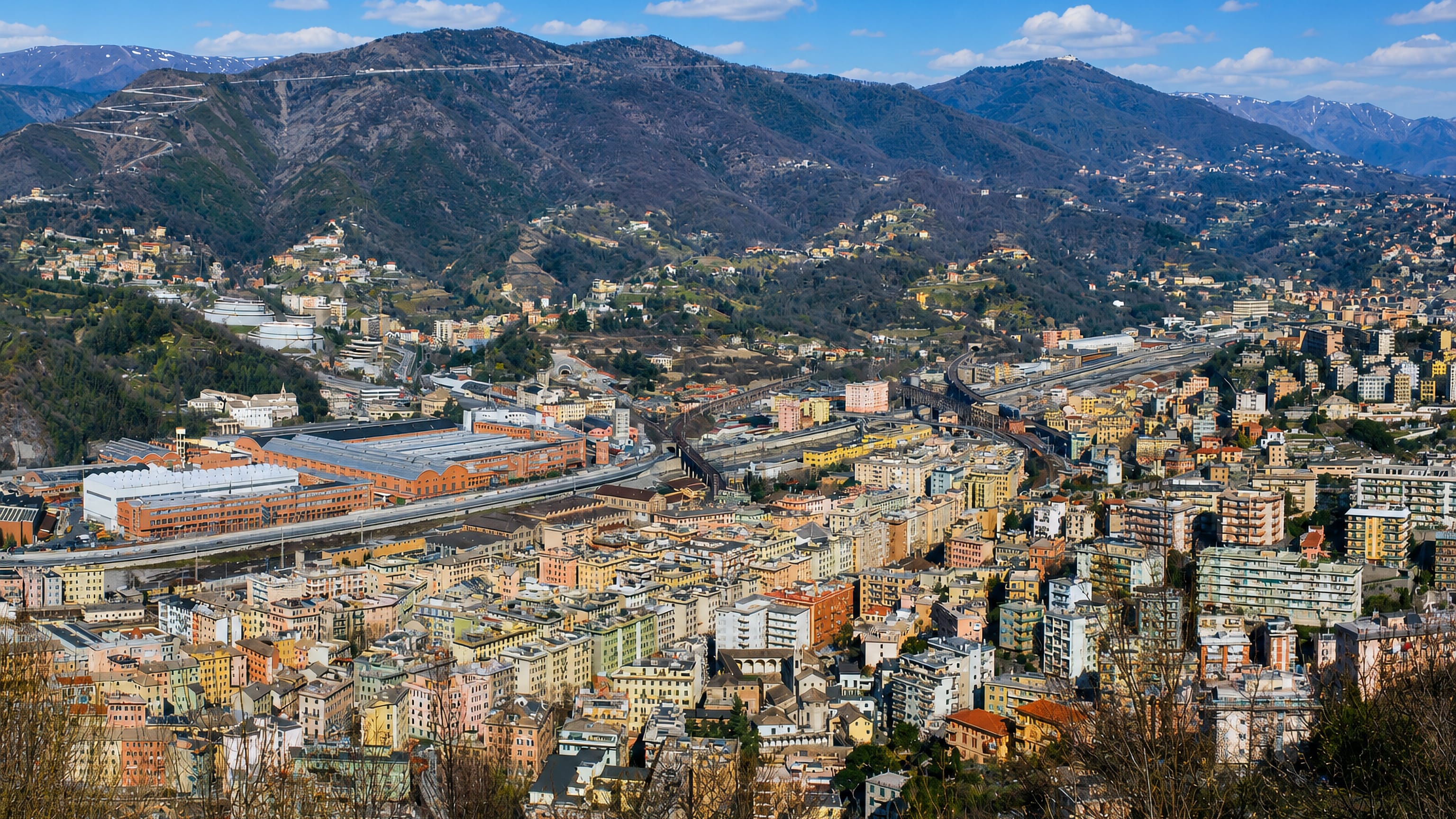 Rivarolo Ligure's pastel blocks, rail yards and industrial sheds filling Genoa's Polcevera valley