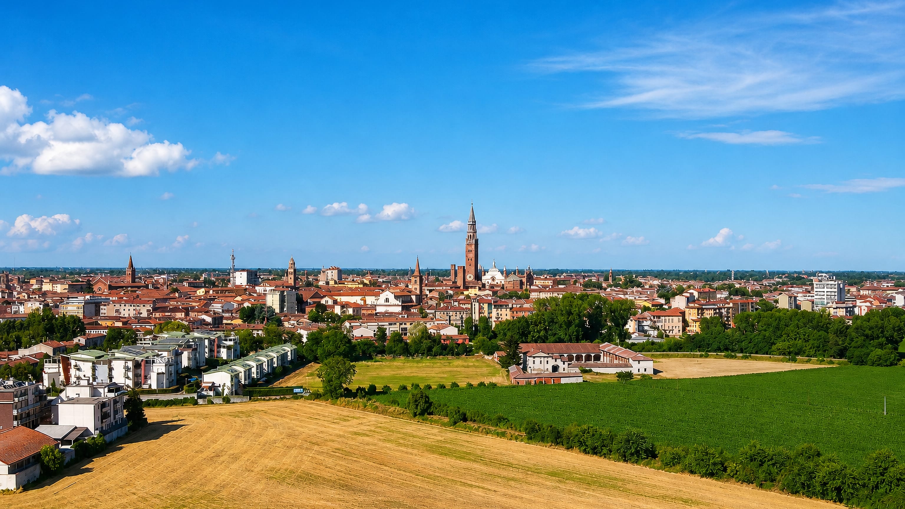 Cremona's skyline across Po Valley farmland, dominated by the brick Torrazzo bell tower beside the cathedral.