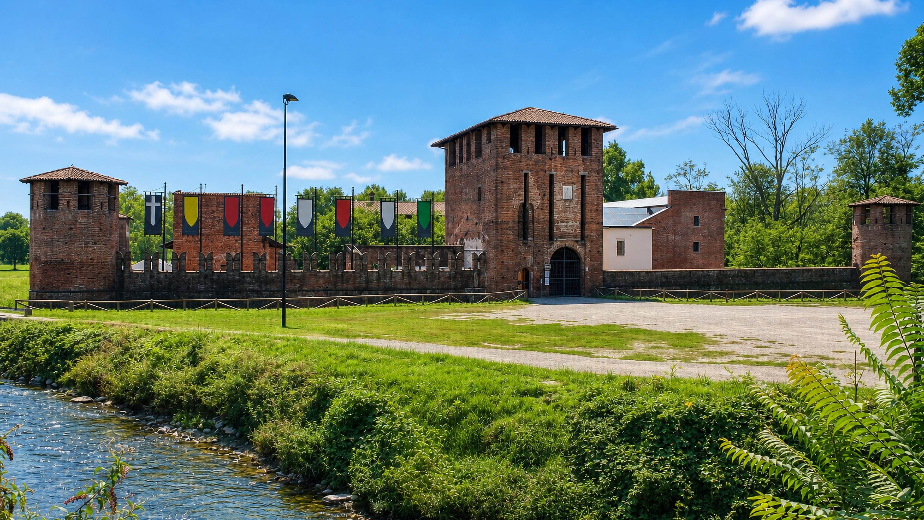 Legnano's brick Castello Visconteo beside the Olona river, hung with the coloured banners of its contrade.