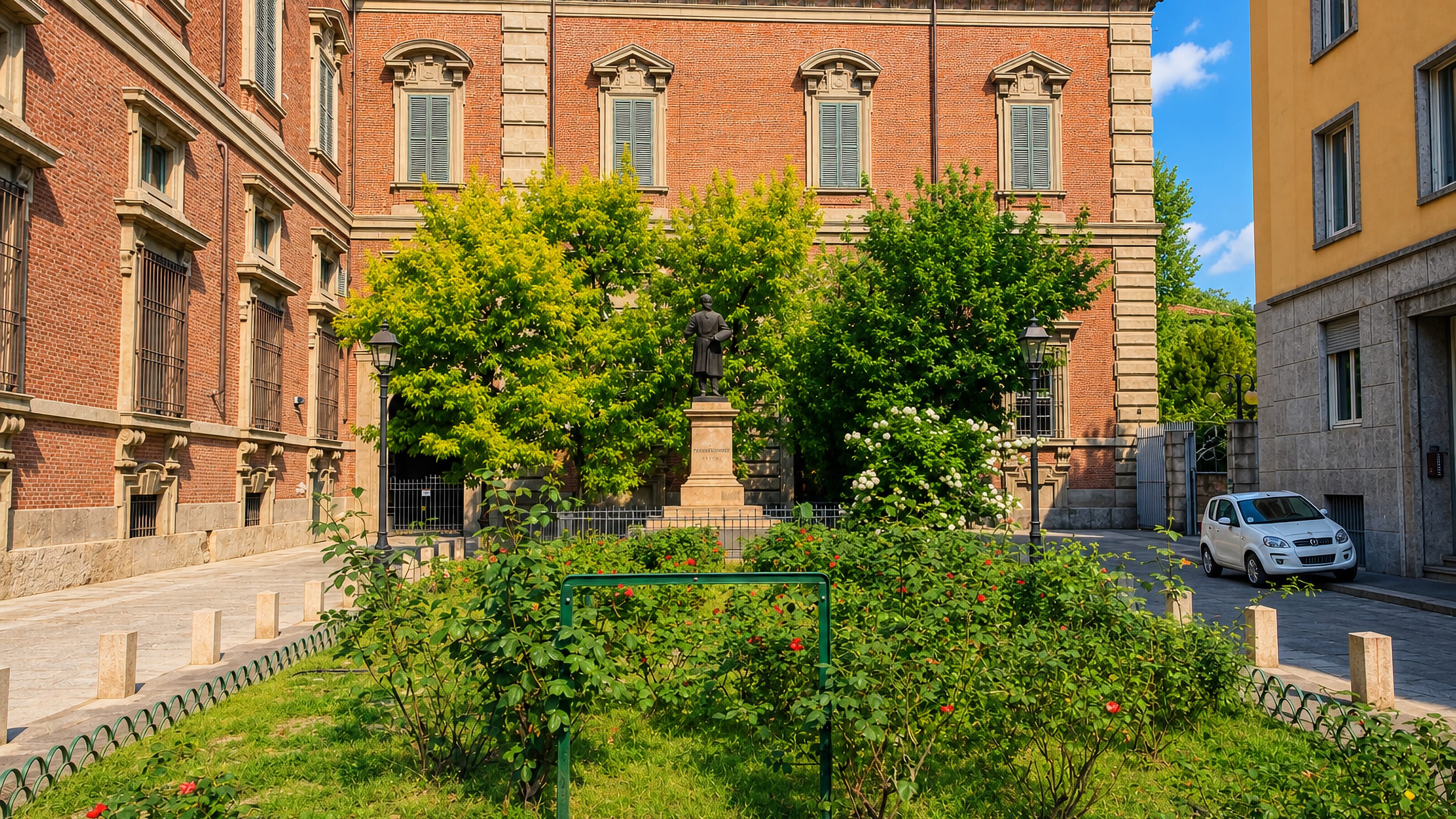 Brick palazzo facade, a bronze statue and rose beds on a quiet street in Milan's Brera district