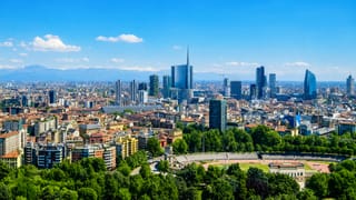 Milan's Porta Nuova skyline with the UniCredit Tower and Bosco Verticale, snow-capped Alps beyond and the Arena Civica below.