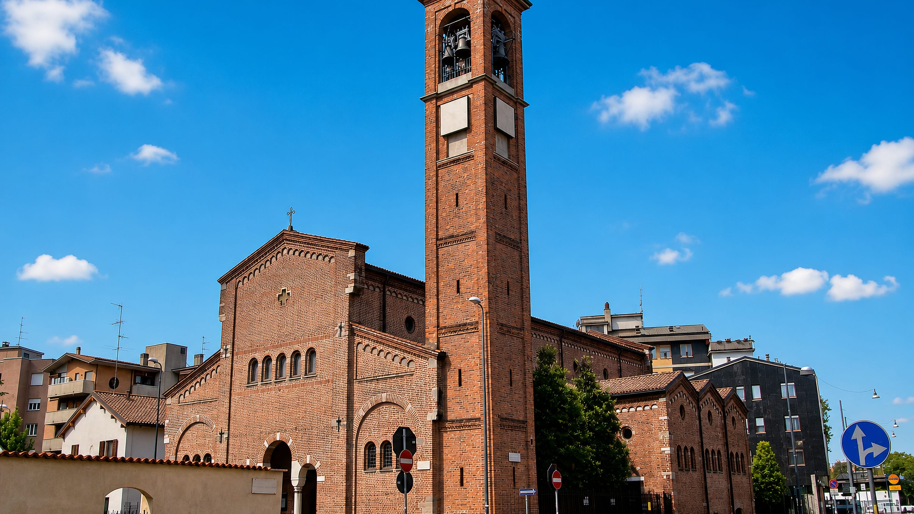 Red-brick parish church and tall campanile among apartment blocks in Lambrate, Milan