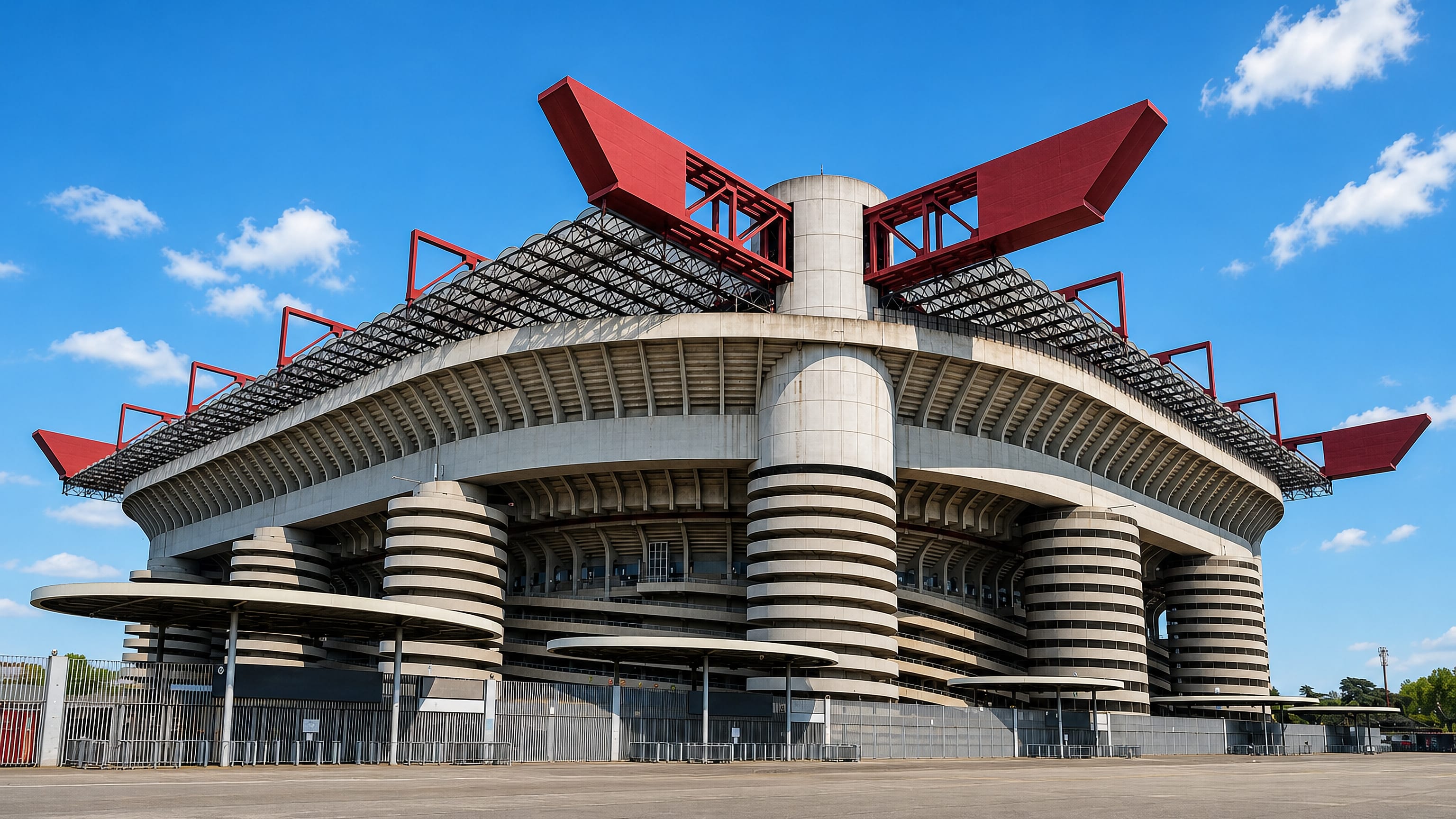 Concrete spiral ramps and red roof girders of the San Siro stadium in Milan under a clear sky.