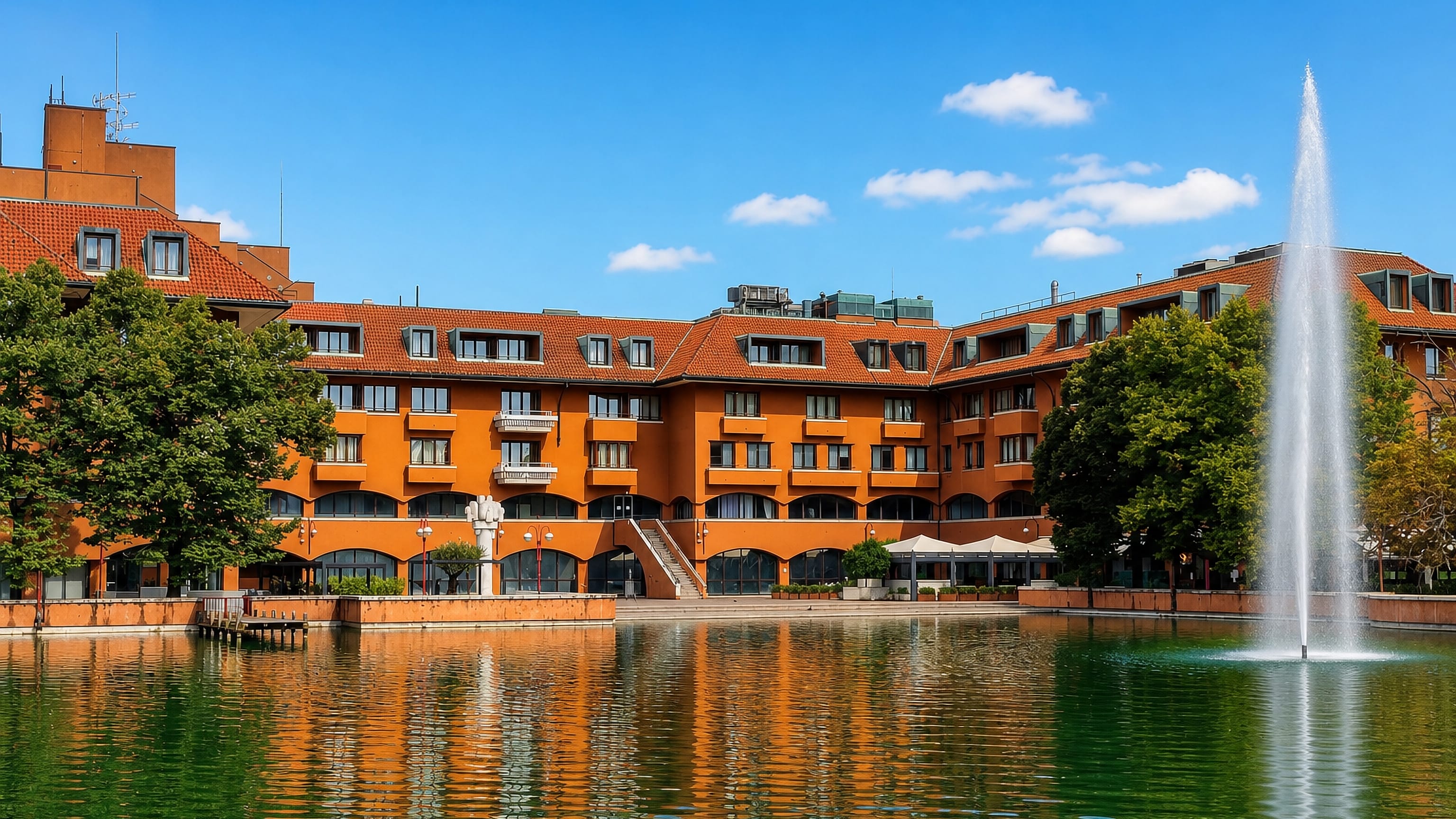 Terracotta apartment blocks and a fountain on the artificial lake at Milano Due, Segrate, near Milan.