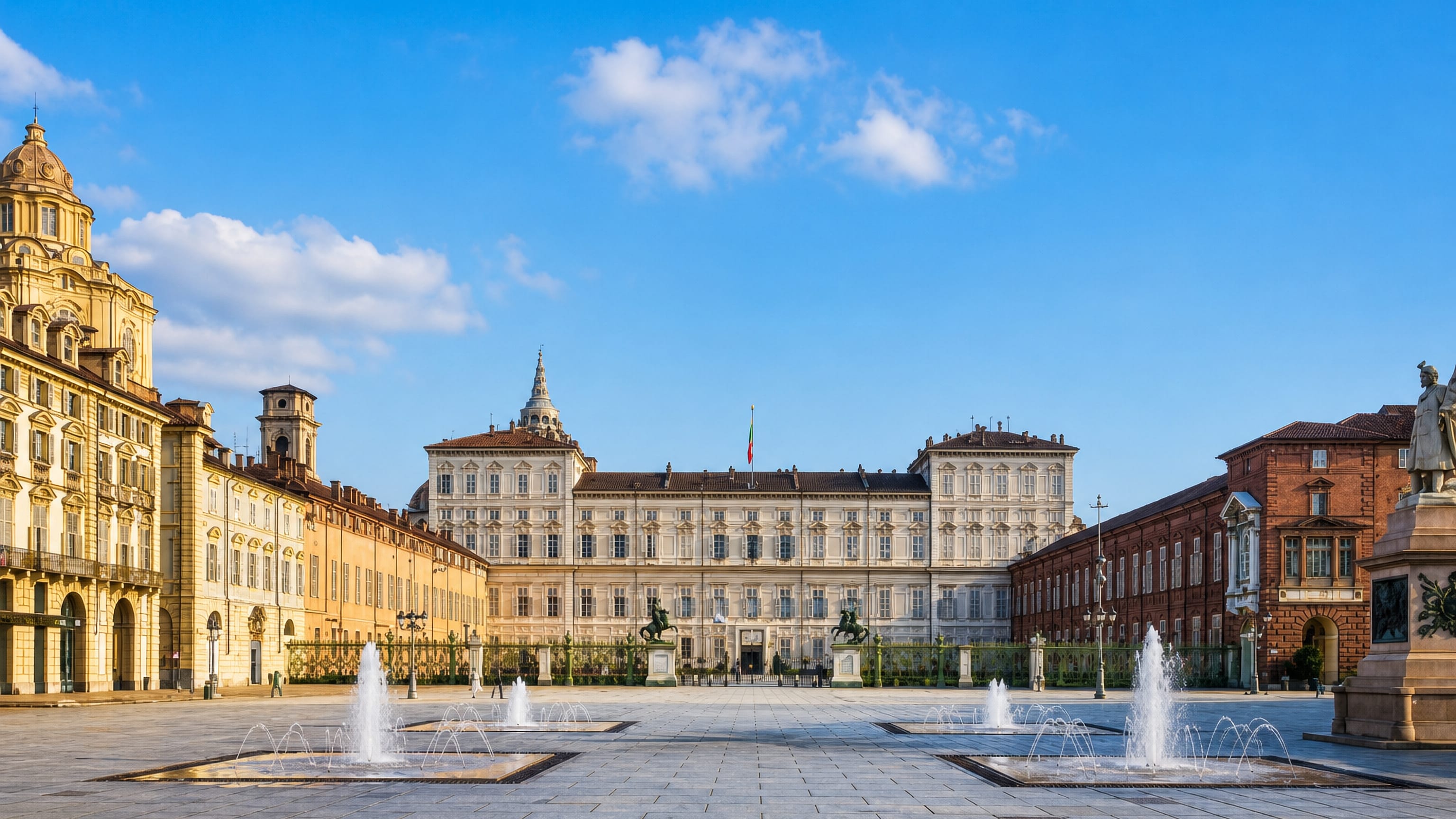 Piazza Castello in Turin with the Royal Palace, its Dioscuri statues and the square's fountains under a clear sky.