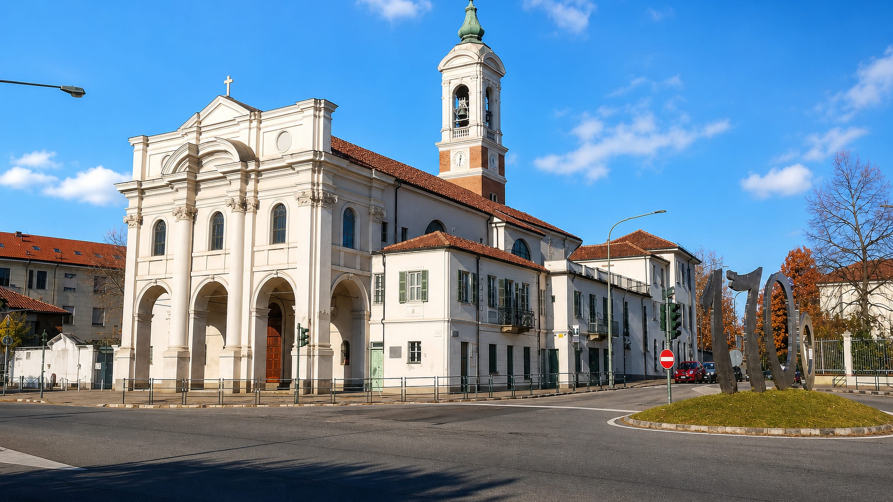 A baroque parish church with bell tower beside a roundabout in Lucento, Turin.