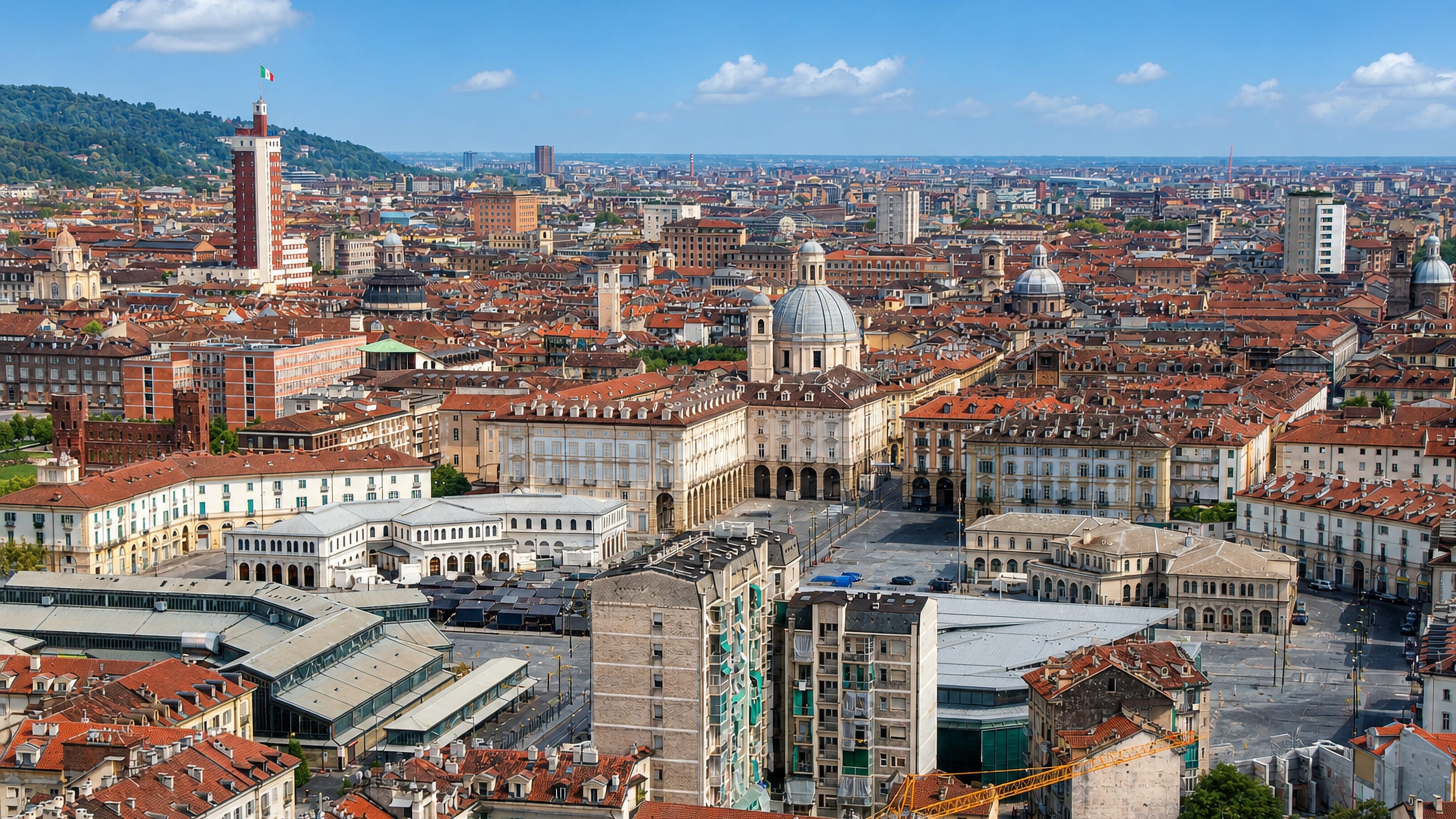 Turin's terracotta rooftops around the arcaded Porta Palazzo square, with the Torre Littoria and hills beyond.