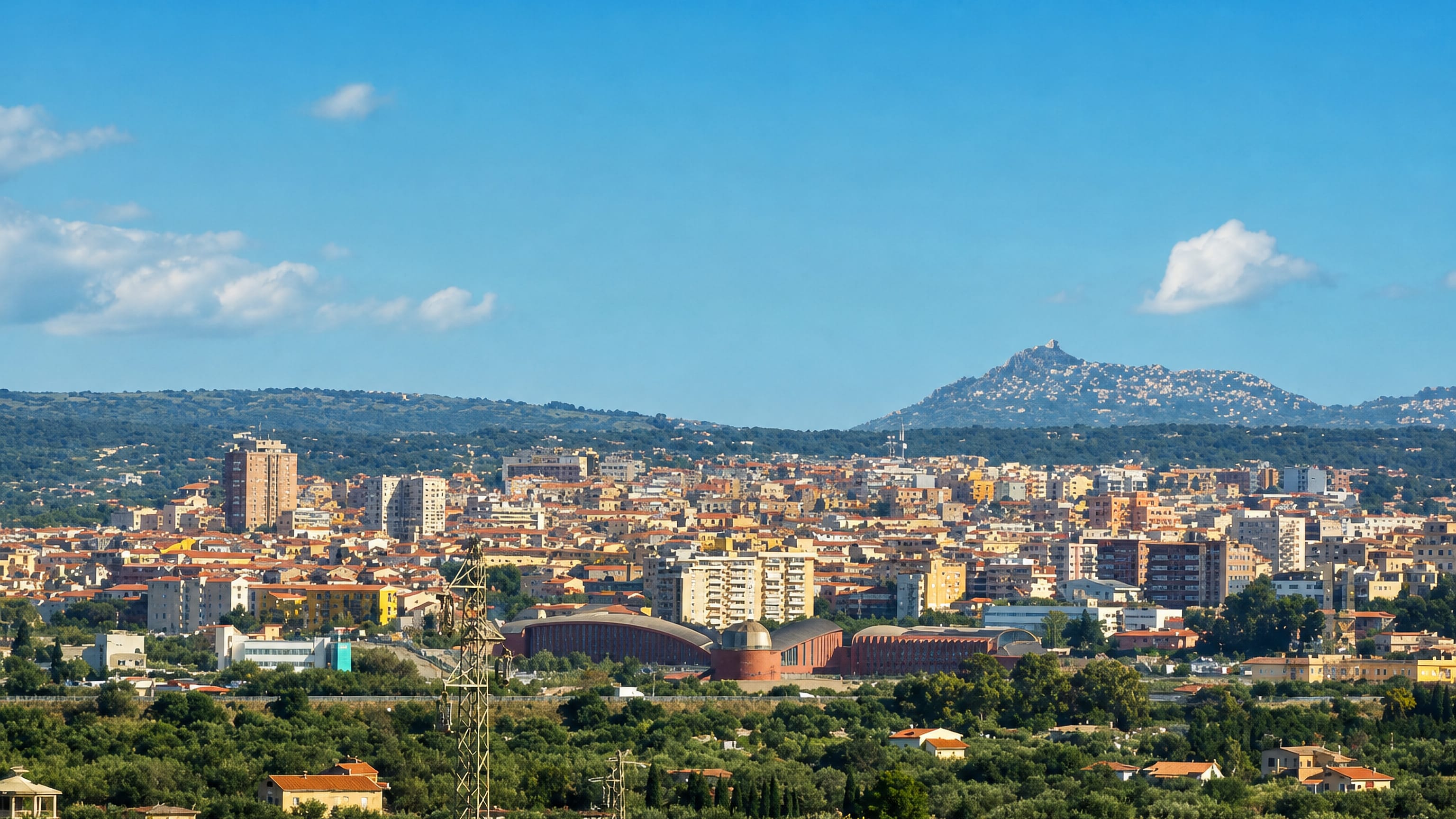 Sassari spread across a Sardinian hillside, pale apartment blocks and red-tiled roofs above olive groves.