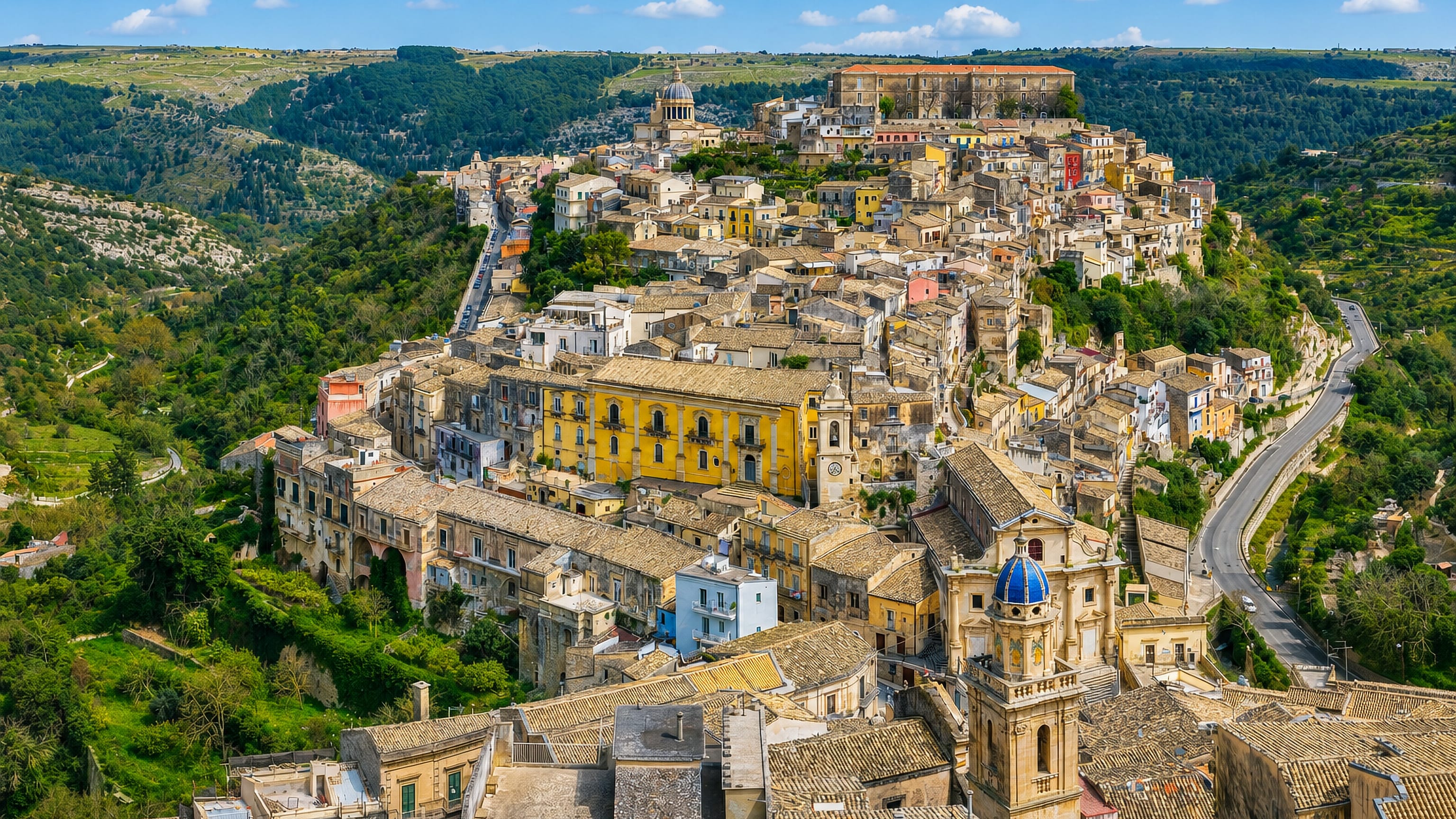 Hilltop rooftops of Ragusa Ibla in Sicily, with the blue majolica dome of Santa Maria dell'Itria in the foreground.