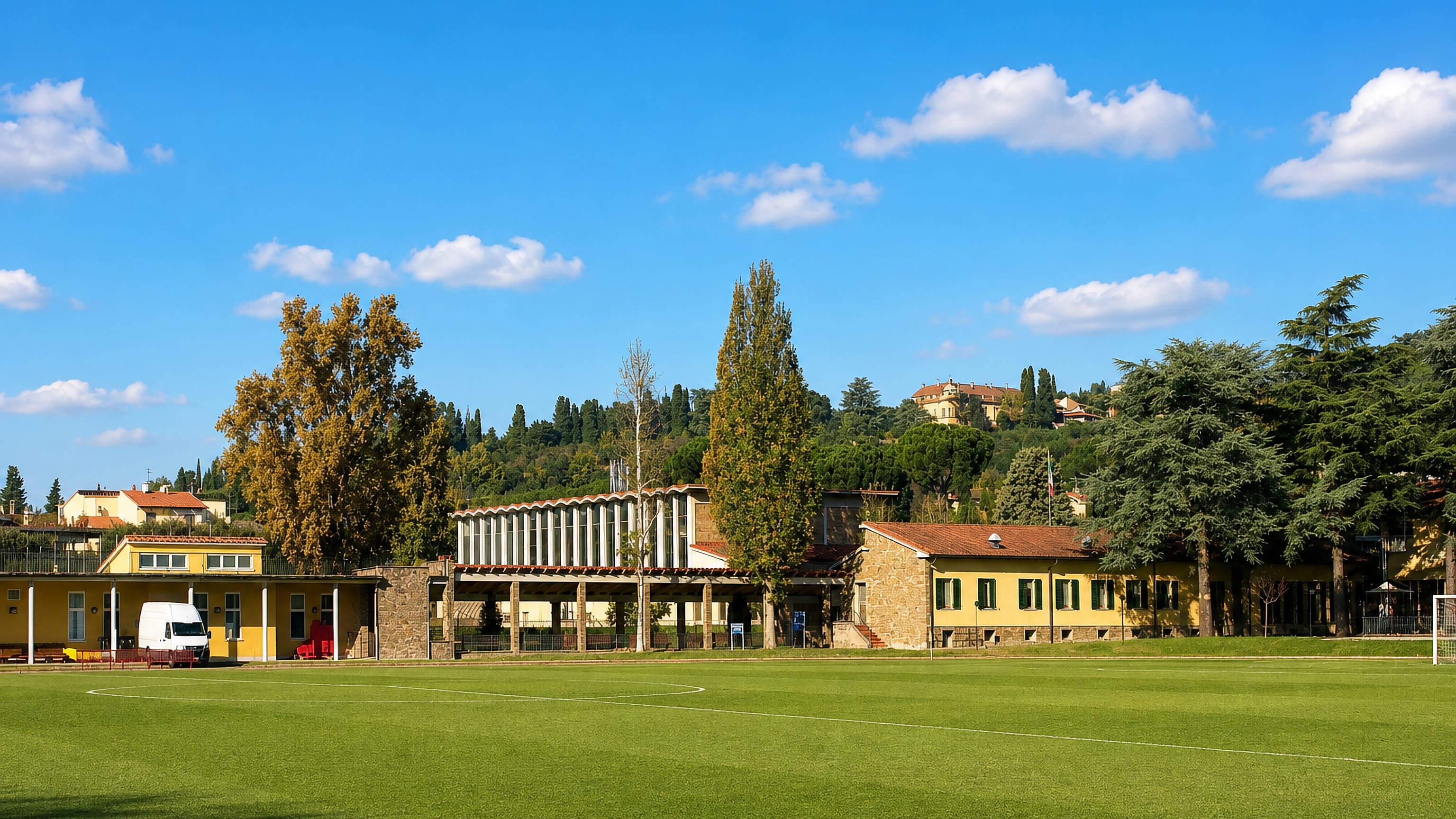 Football pitch backed by stone clubhouse buildings and Tuscan hills in Coverciano, Florence.