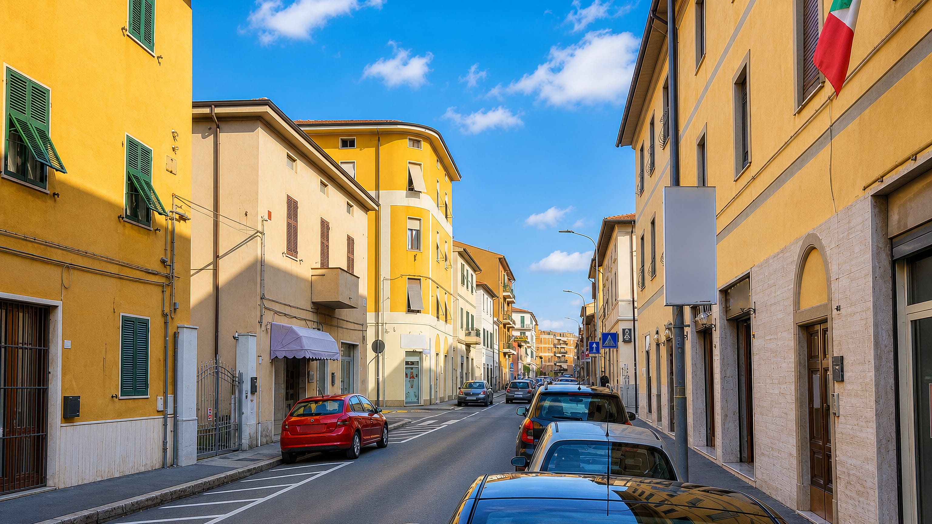 Ochre apartment houses with green shutters lining a quiet residential street in Borgo Tripoli, Grosseto.