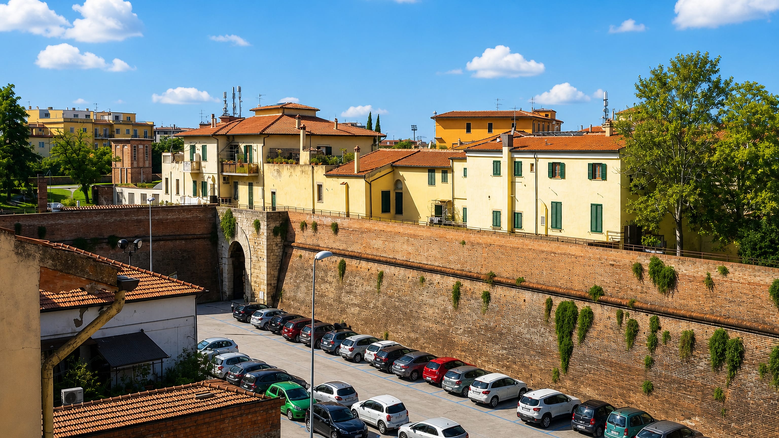 The brick Medici walls and arched gate at Porta Vecchia in Grosseto, with tiled rooftops rising behind.