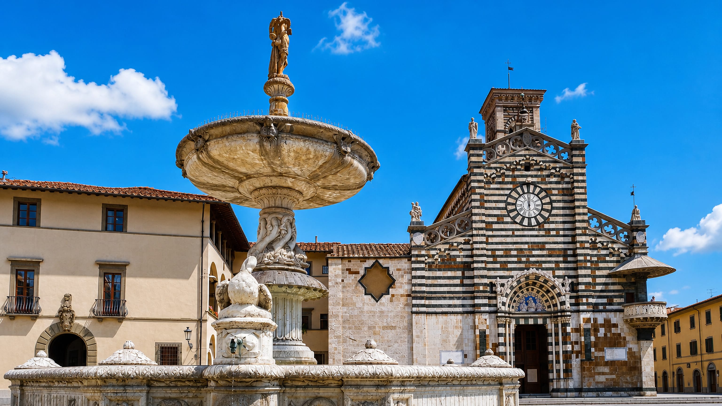 Prato's striped marble Cattedrale di Santo Stefano behind the carved stone fountain on Piazza del Duomo.