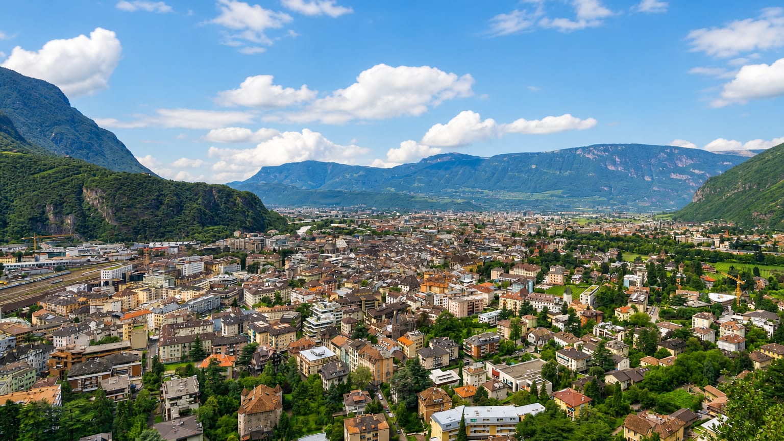 Bolzano nestled in the Adige valley surrounded by Dolomite mountains under a partly cloudy sky