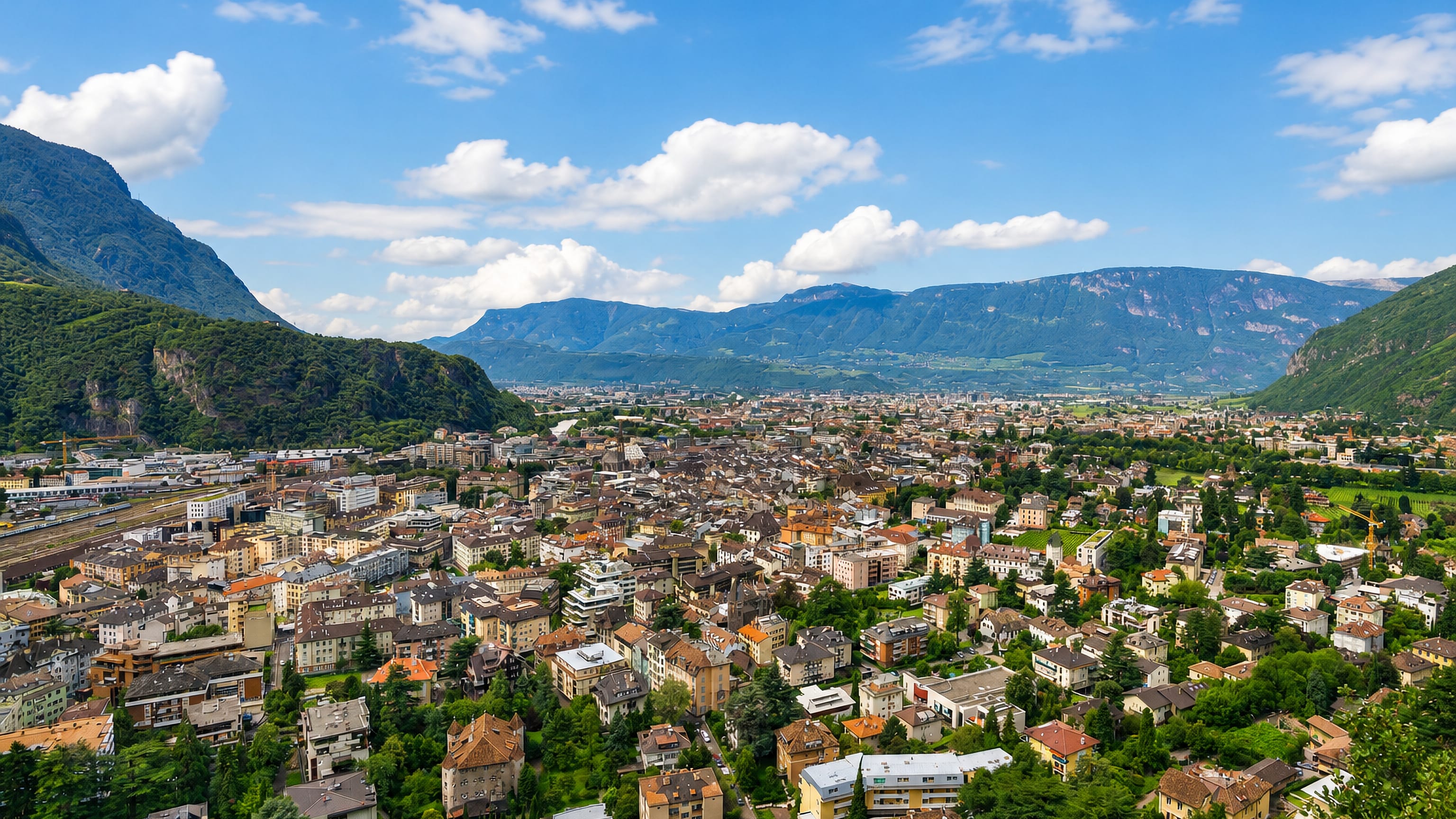 Bolzano nestled in the Adige valley surrounded by Dolomite mountains under a partly cloudy sky