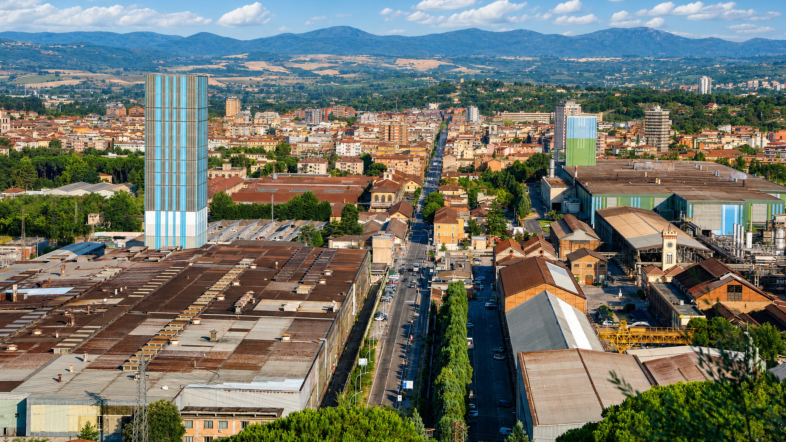 Aerial view over Terni's steelworks and rooftops toward the Umbrian hills, the city's glass high-rise at centre