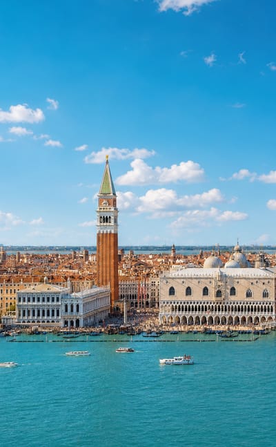 Waterfront view of Venice with St Mark's Campanile, the Doge's Palace and boats on the lagoon under a bright sky