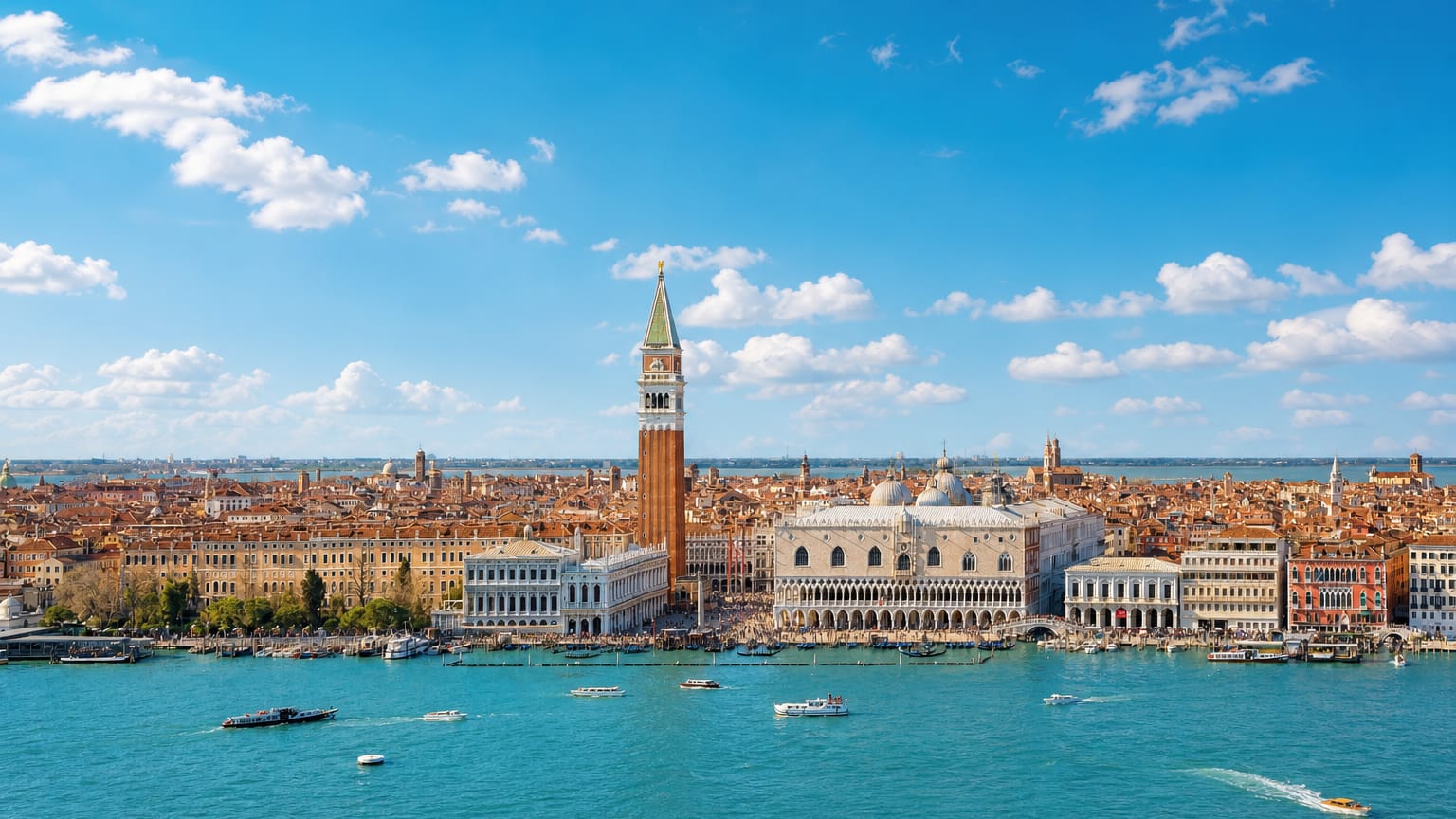 Waterfront view of Venice with St Mark's Campanile, the Doge's Palace and boats on the lagoon under a bright sky