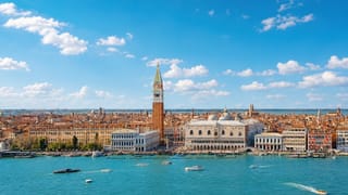 Waterfront view of Venice with St Mark's Campanile, the Doge's Palace and boats on the lagoon under a bright sky