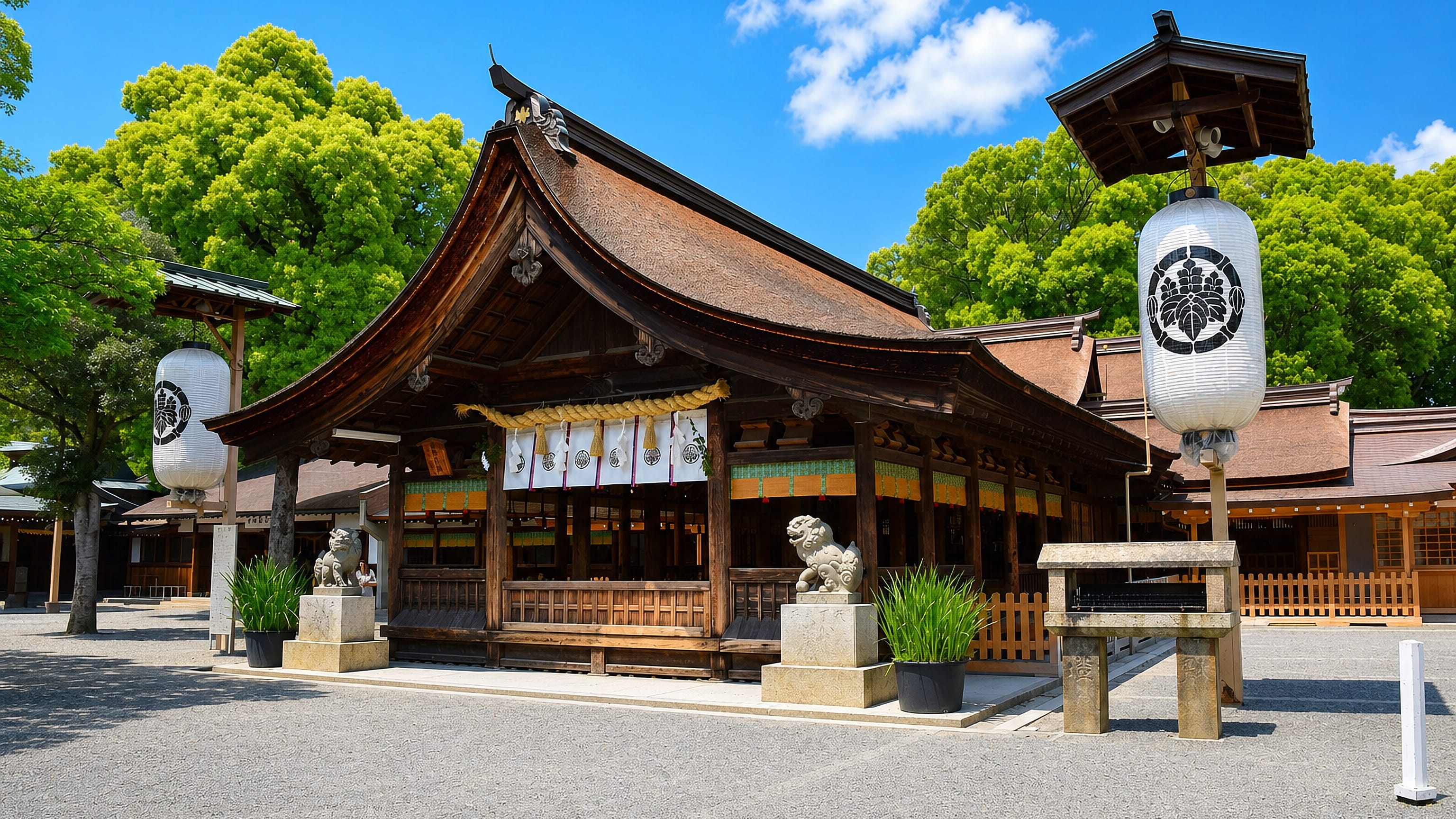 Wooden Shinto shrine hall with stone lion-dogs and white paper lanterns in Inazawa, Japan