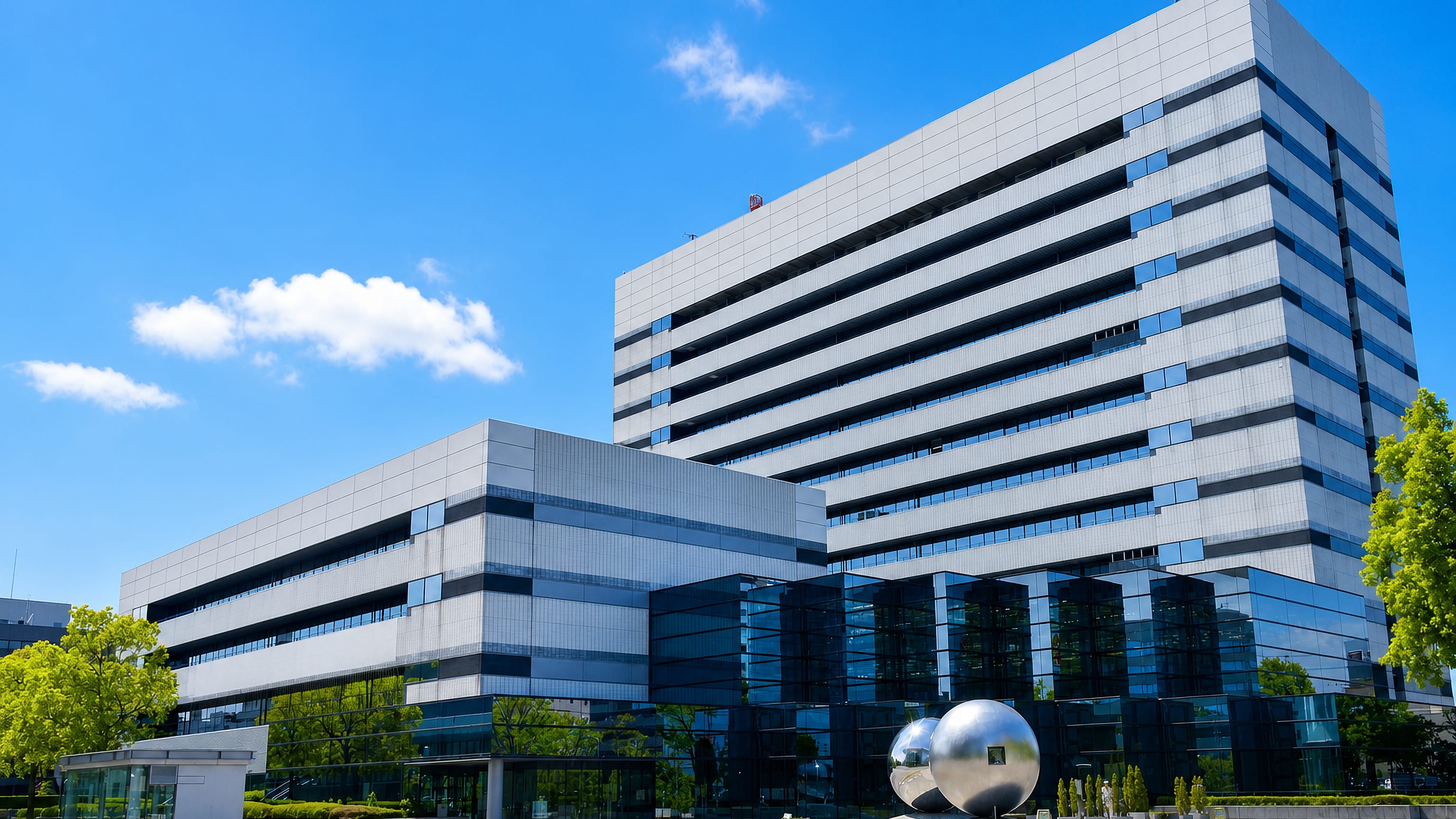 Modern glass-and-steel civic office complex with a mirrored sphere sculpture in Kasugai, Japan