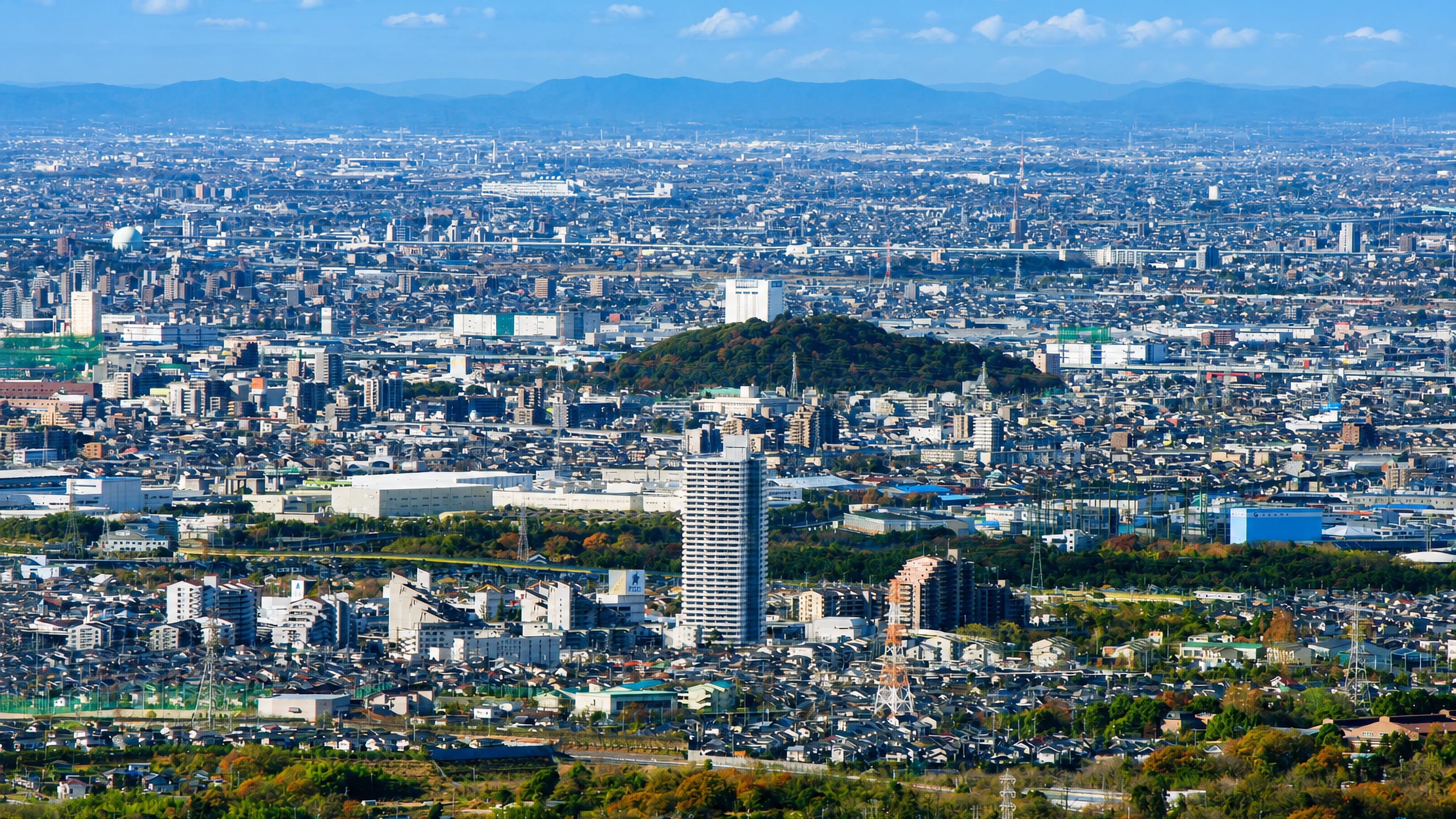 Aerial view over Komaki, Japan, with wooded Mount Komaki rising from the Nobi plain cityscape.