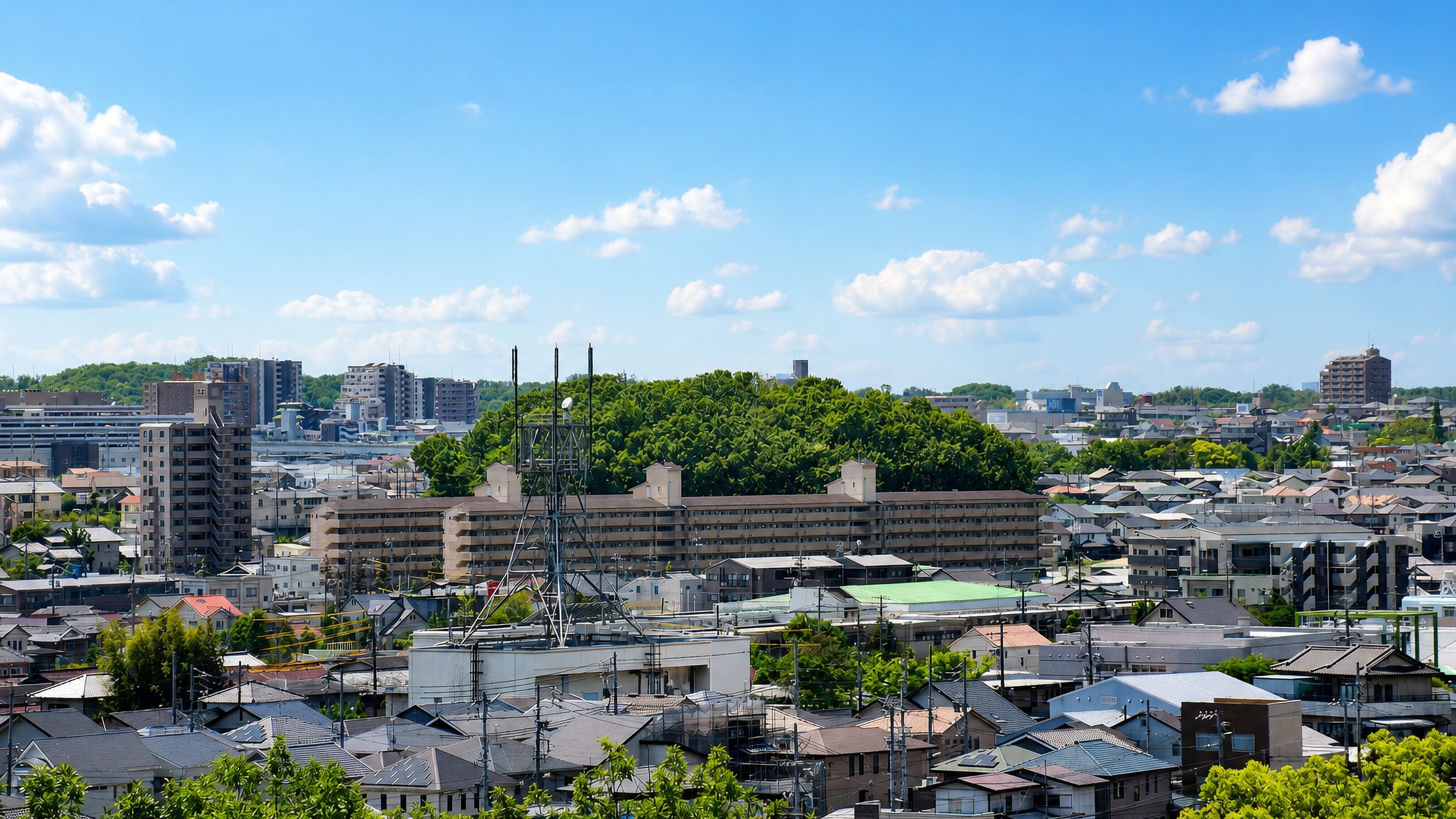Suburban houses and mid-rise apartment blocks below wooded hills in Nagakute, Aichi, Japan