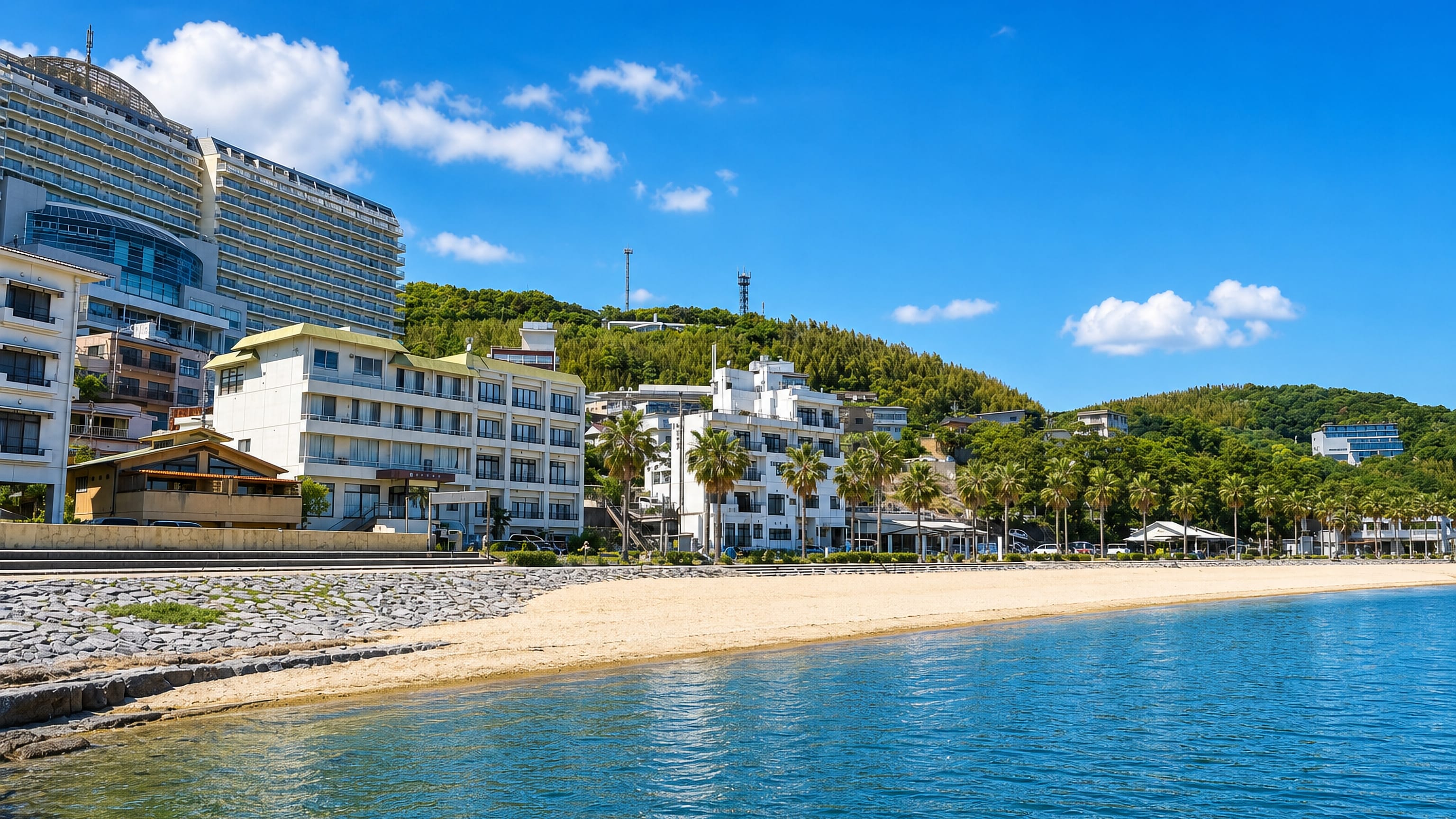 Palm-lined sandy bay backed by resort hotels and wooded hills on the coast of Nishio, Aichi.