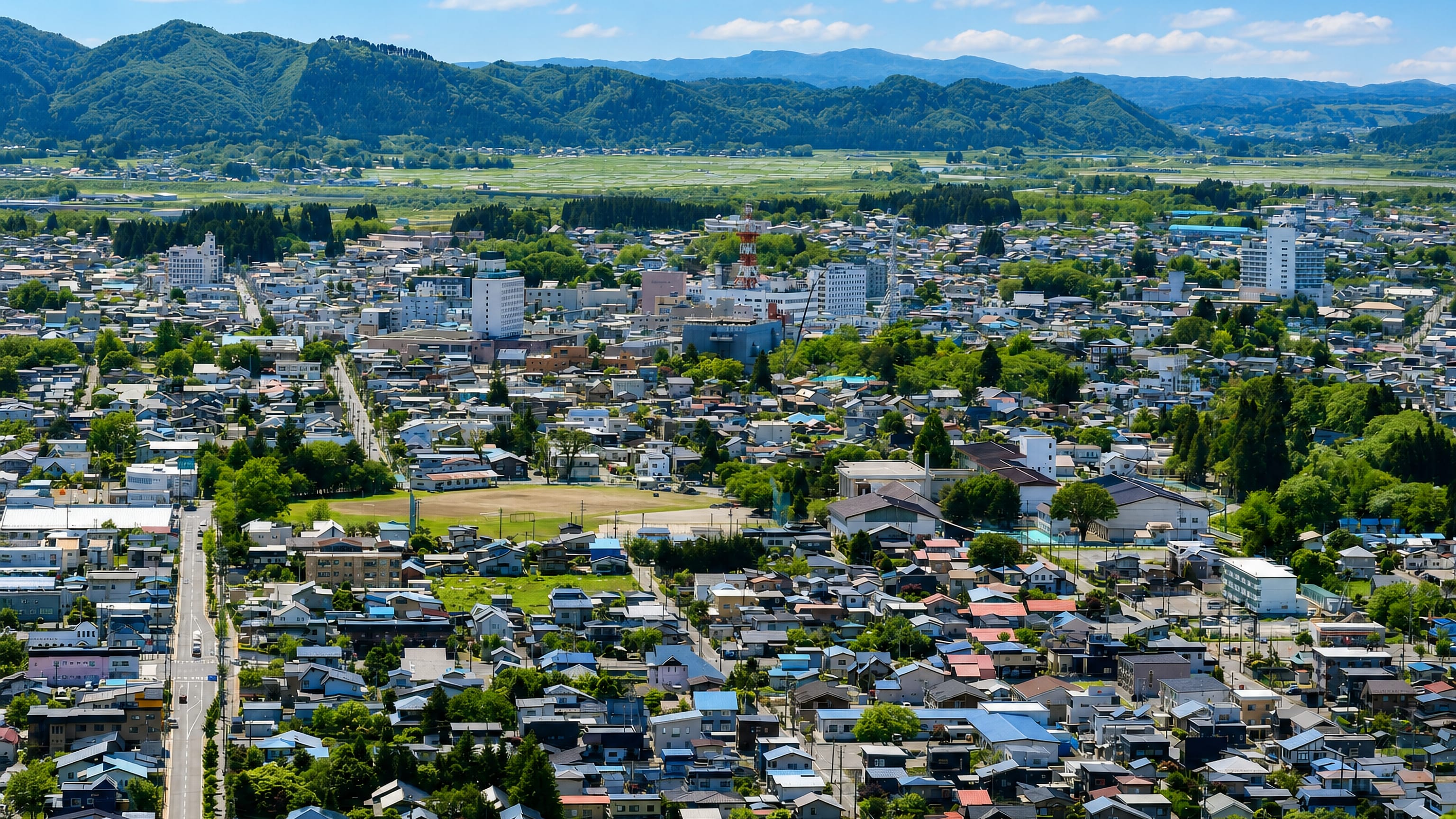 Odate's low-rise townscape spreading across an Akita valley ringed by forested mountains.