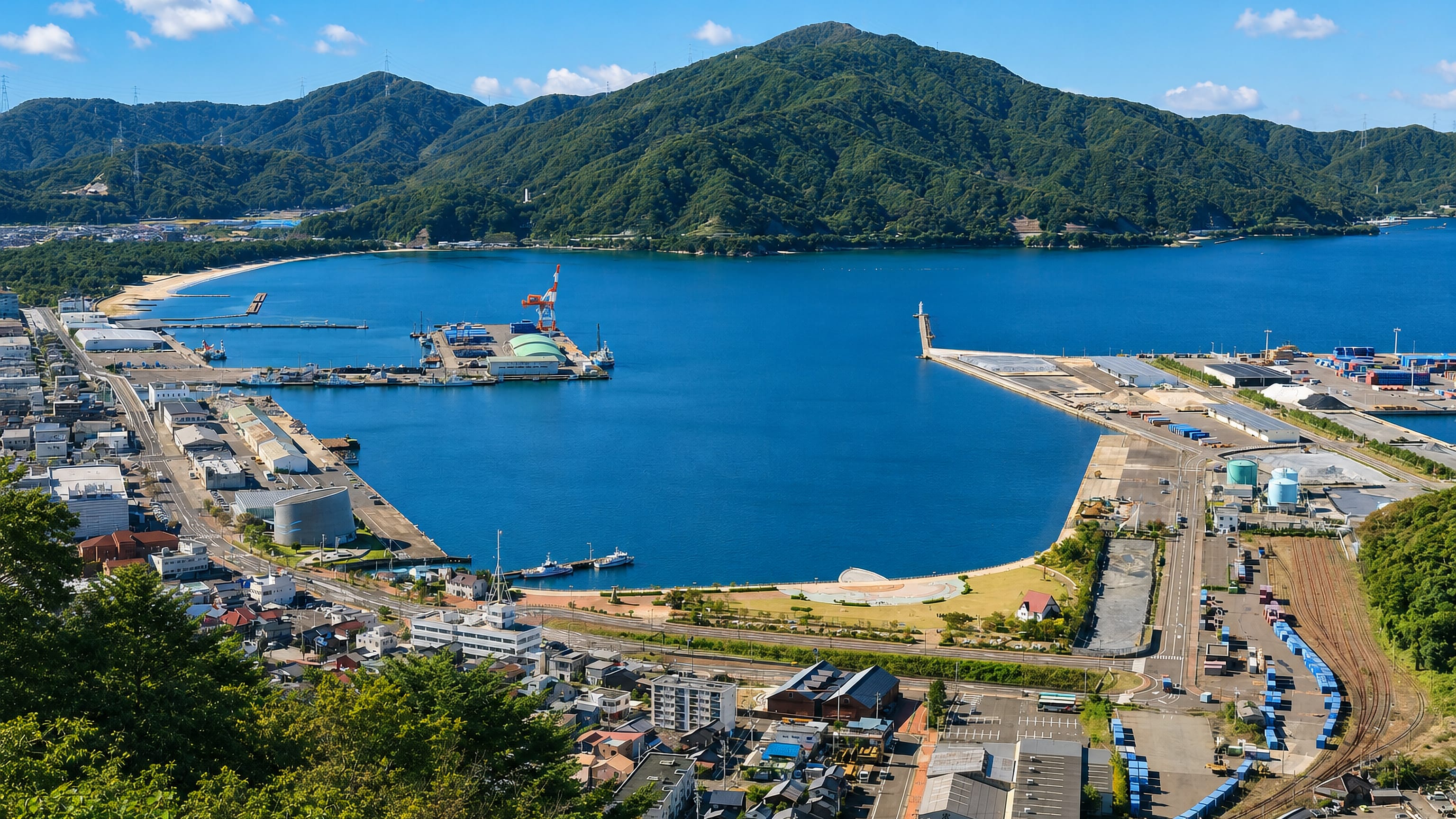 Tsuruga, Japan, seen from above with its harbour, breakwater and green hills ringing Tsuruga Bay.