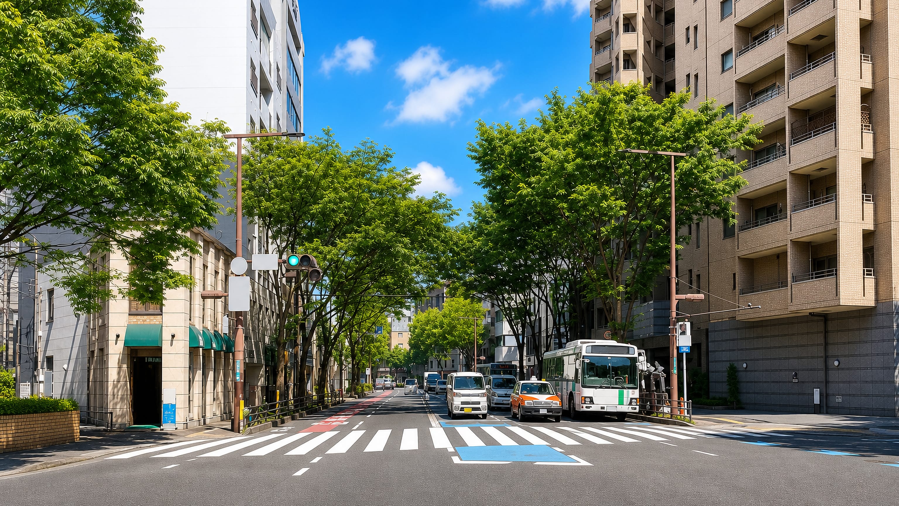Tree-lined avenue with a crossing, bus and apartment blocks in the Daimyo area of central Fukuoka.