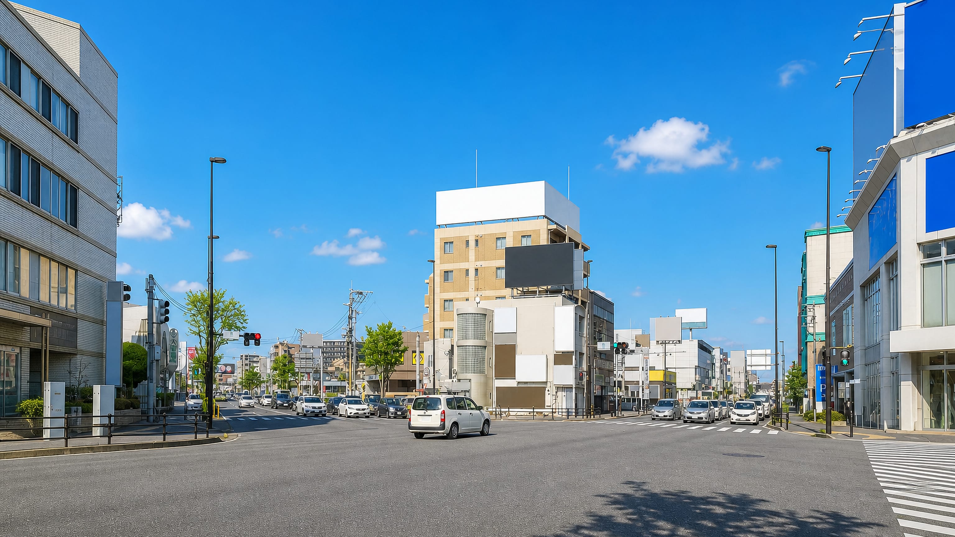 Sunlit crossroads in Hara, Fukuoka, lined with low mid-rise offices and shops under a clear sky.