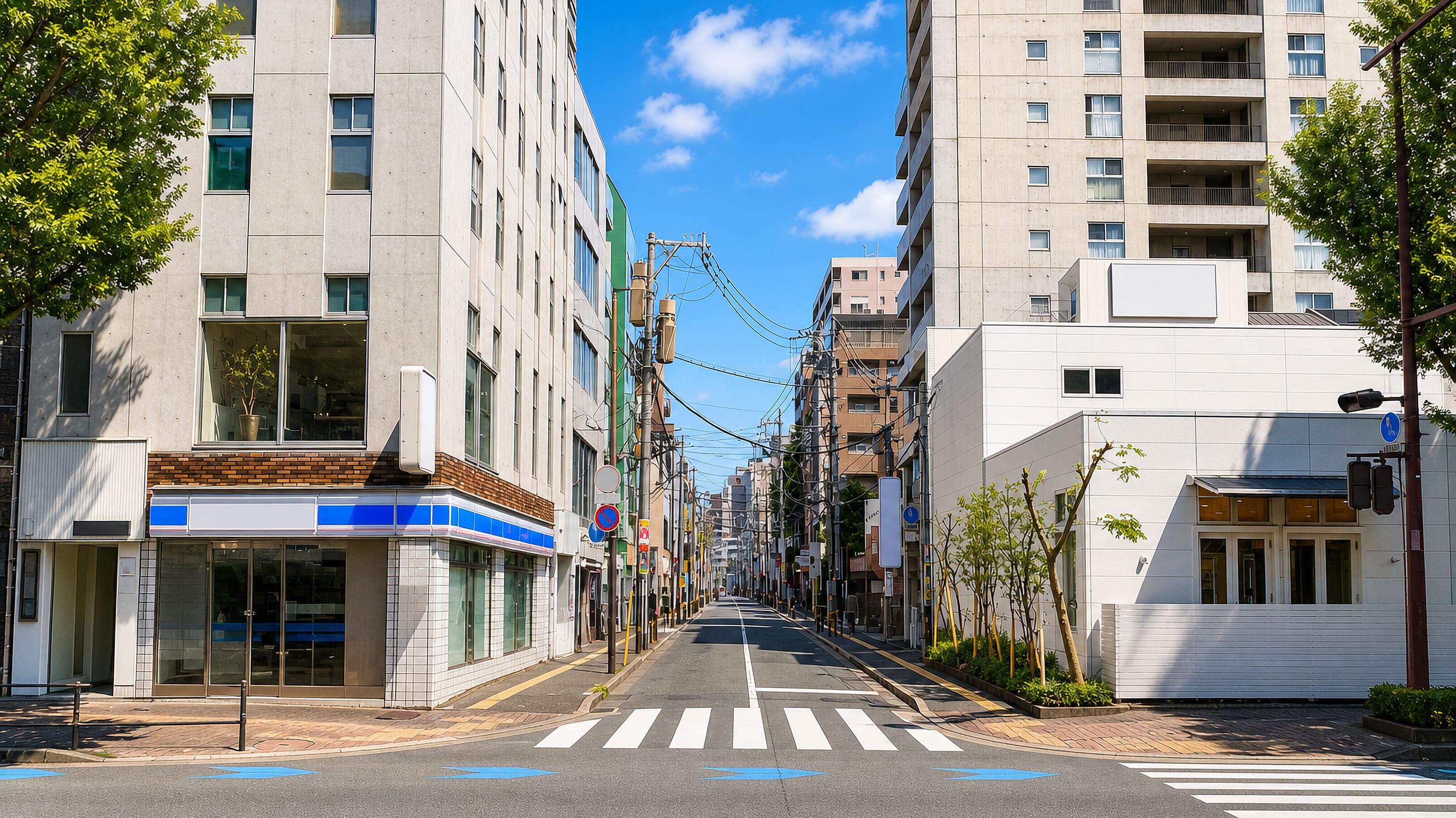 Quiet street of mid-rise blocks, overhead cables and a crosswalk in Imaizumi, Fukuoka