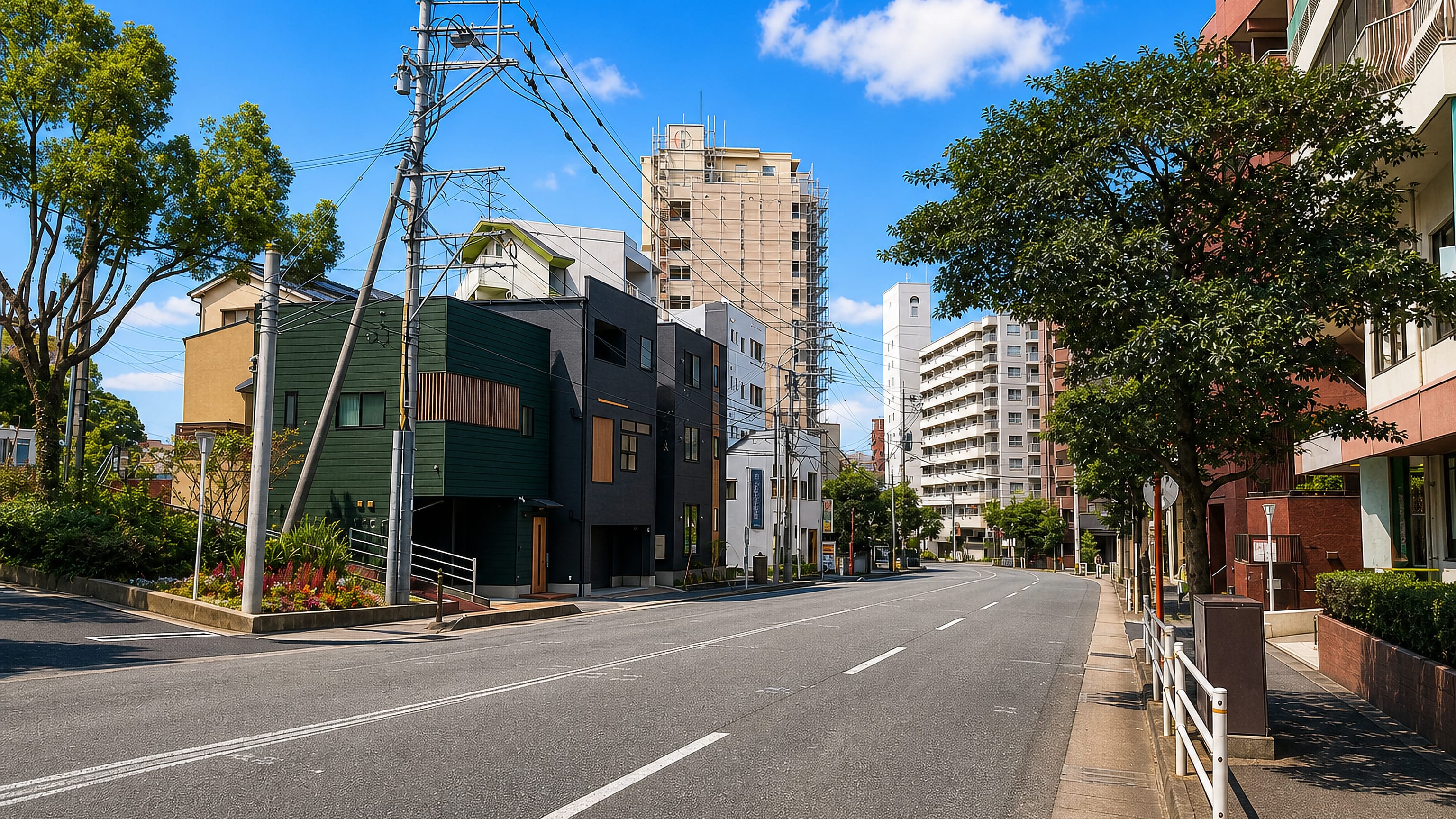 Quiet residential street in Kego, Fukuoka, lined with low houses, overhead power lines and apartment blocks