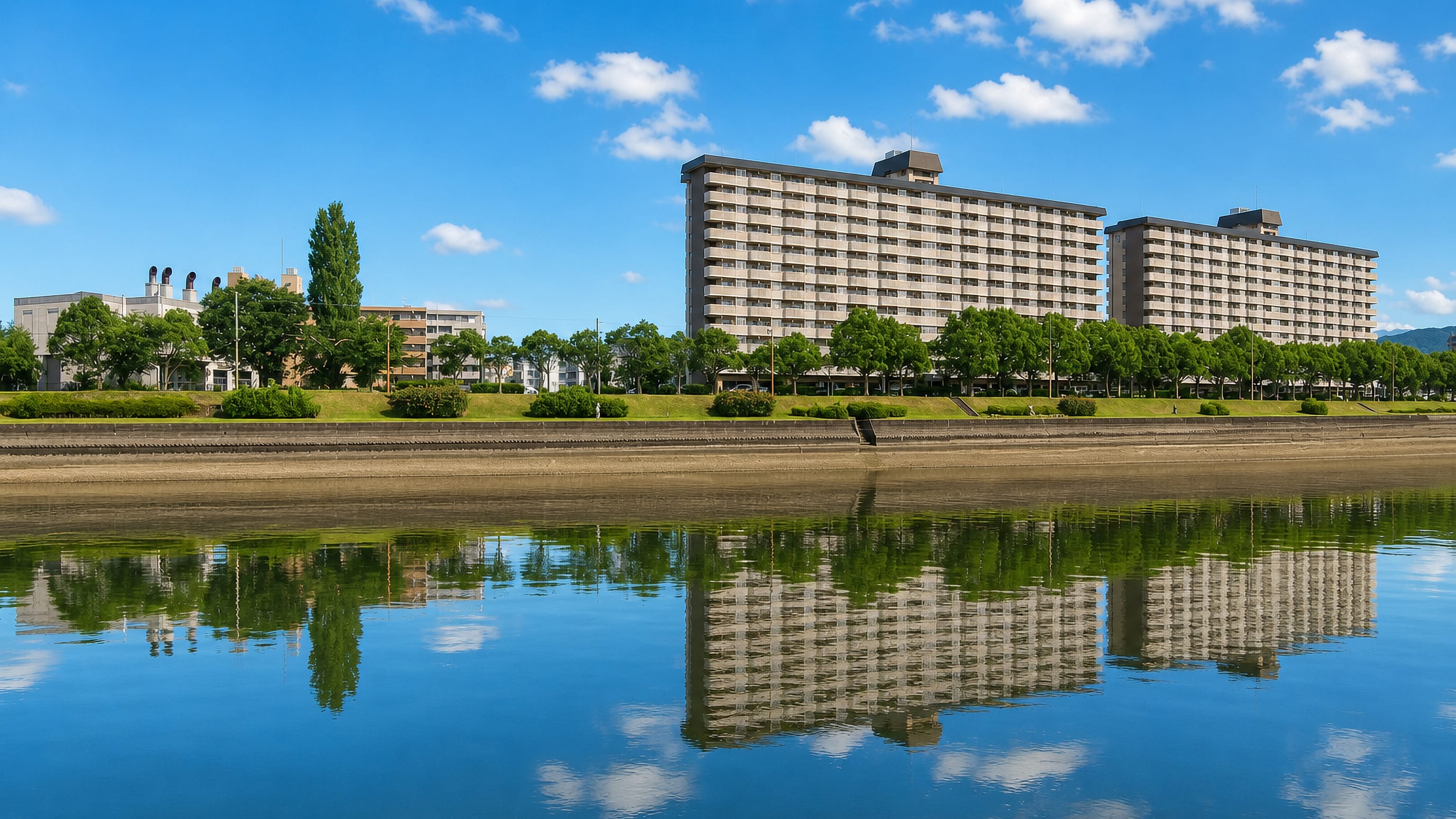 Riverside apartment blocks mirrored in still water at Minamishō, Fukuoka.
