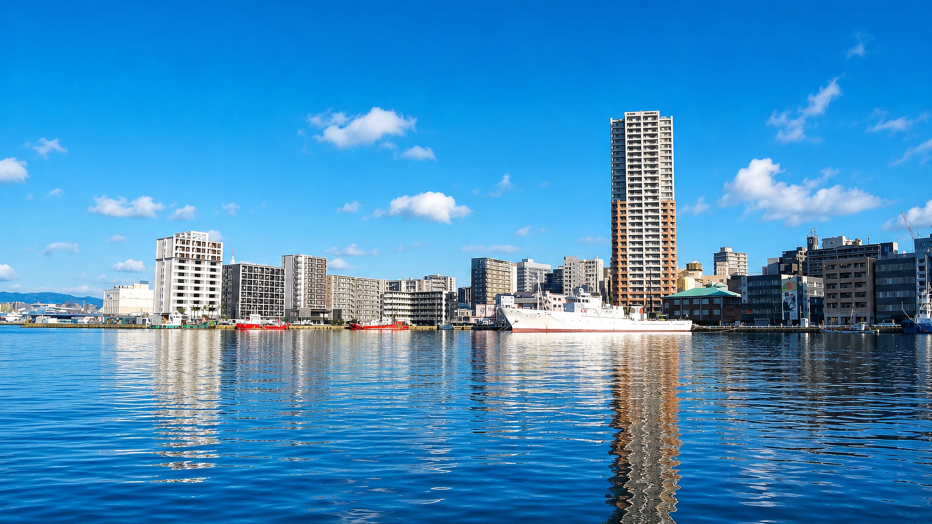 Waterfront apartment towers and a moored white ship across the harbour at Minato in Fukuoka.